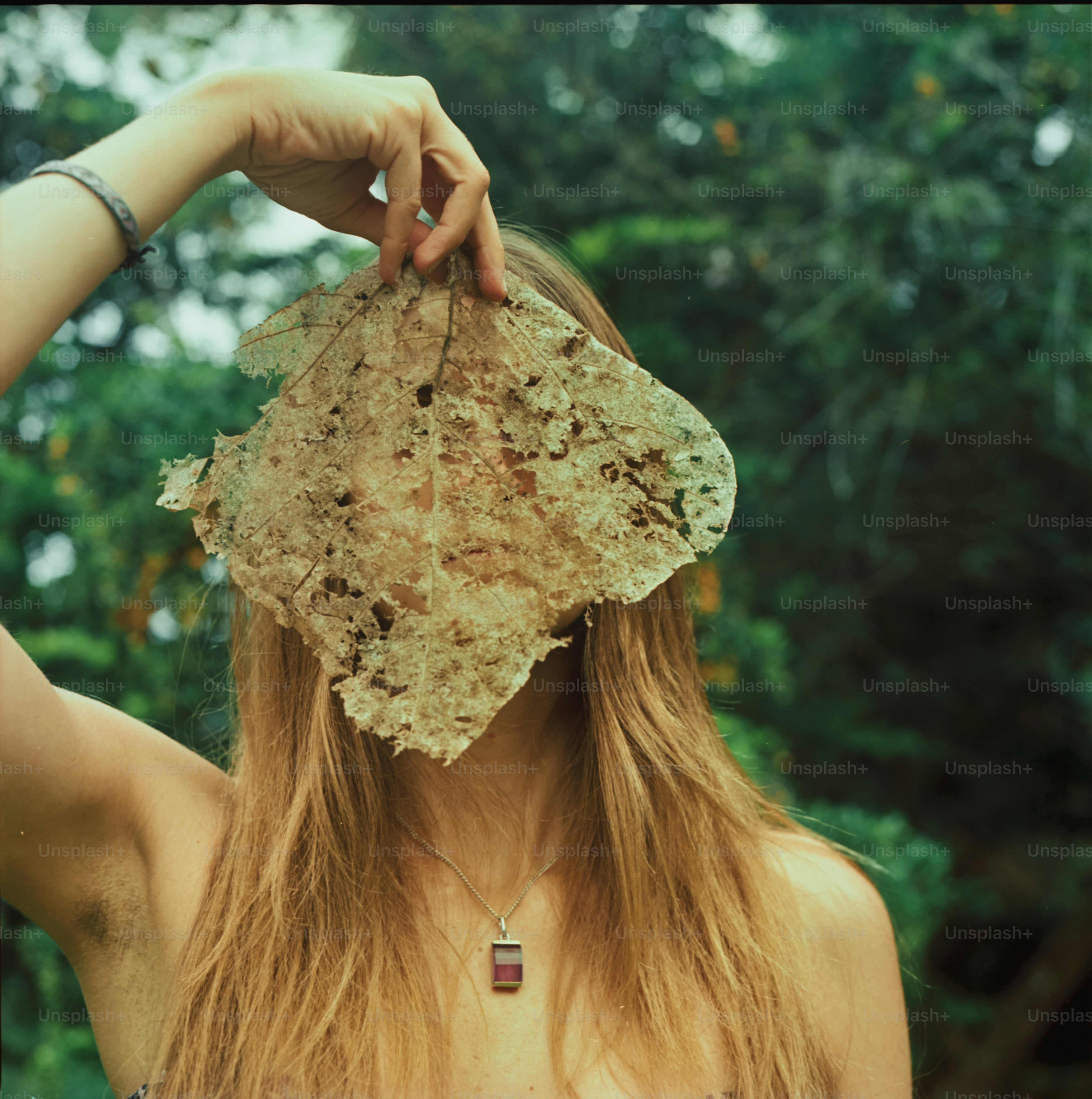 La mujer sostiene una hoja frente a su cara.