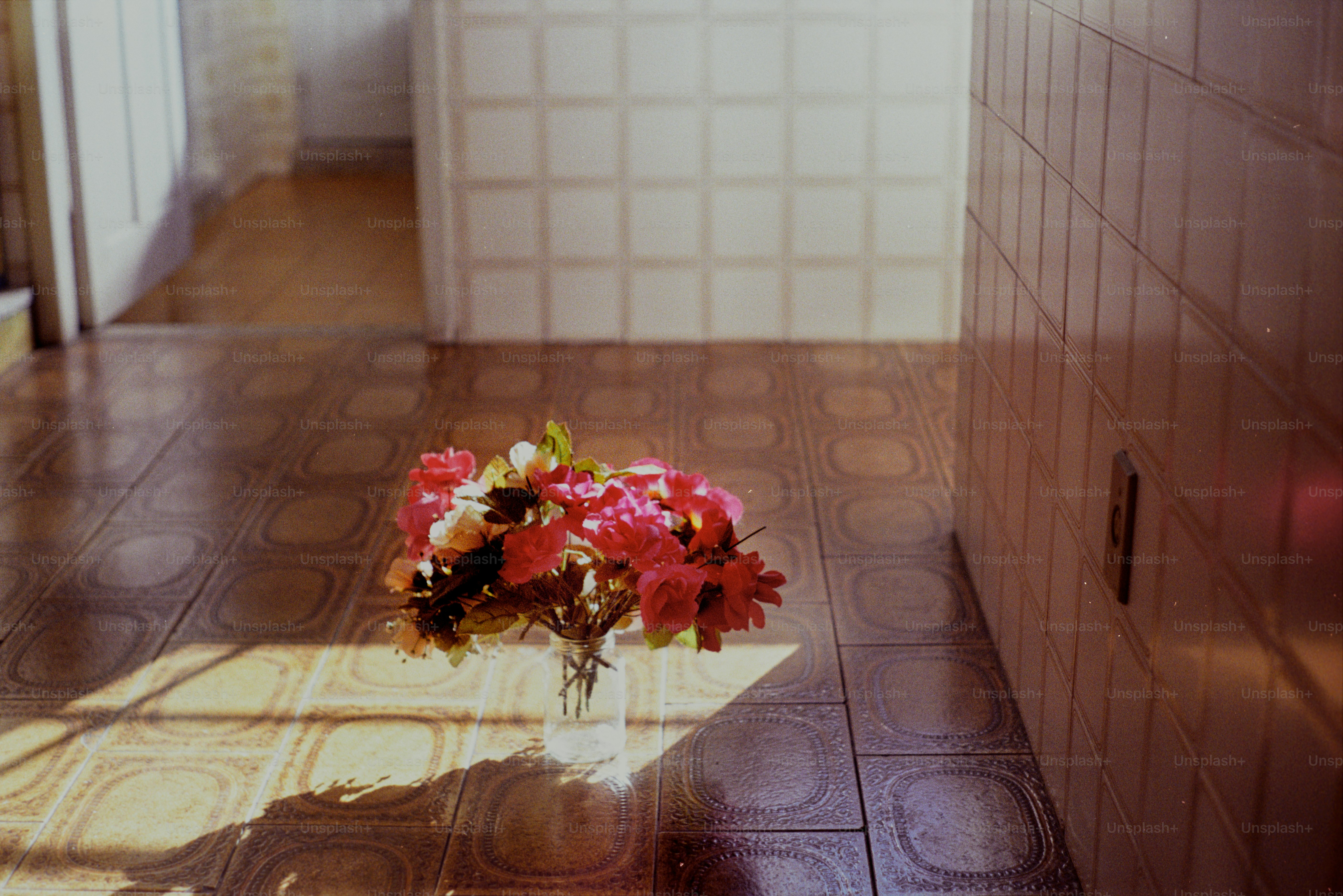 Las flores se encuentran en un piso de baldosas en una habitación soleada.