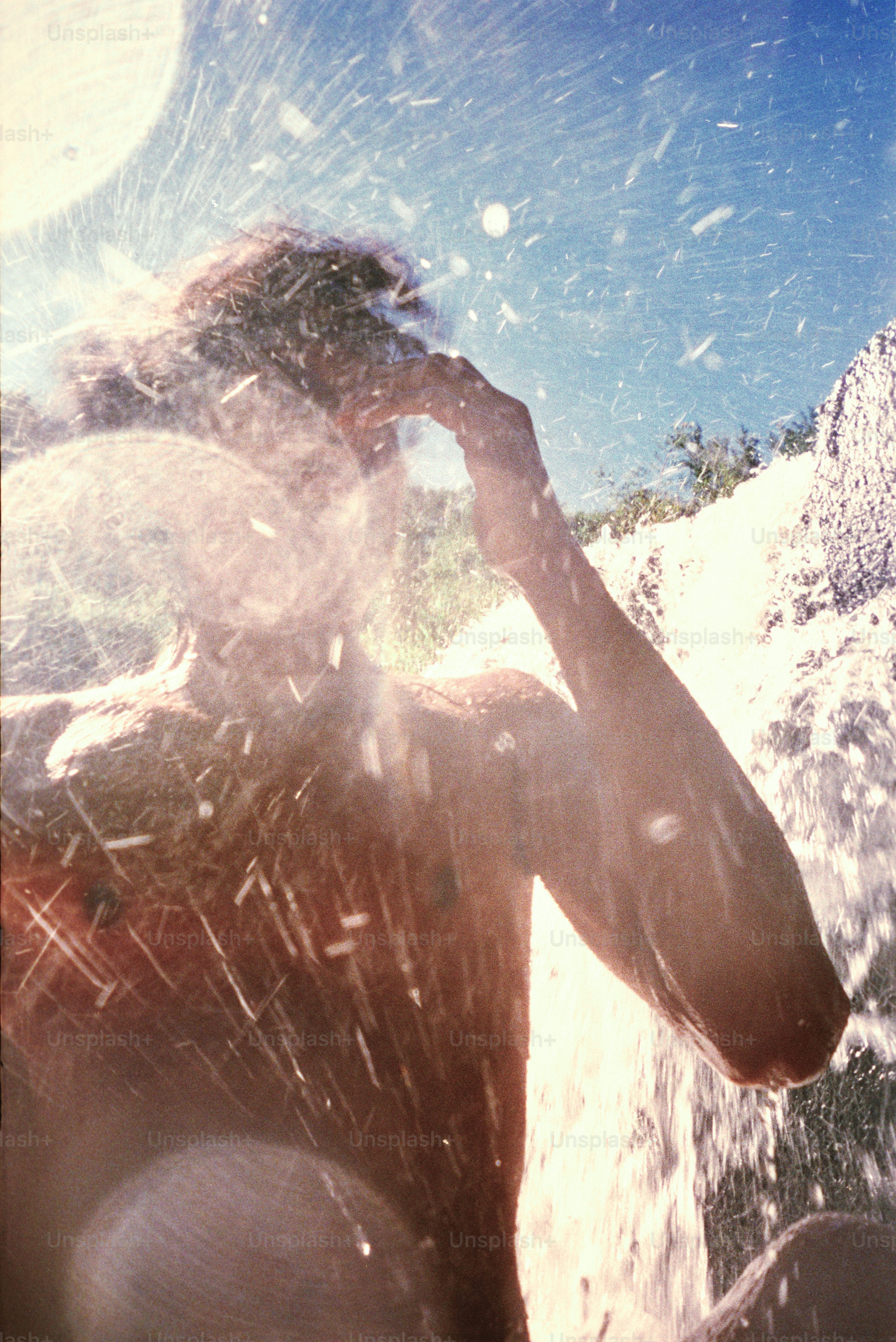 Una persona disfruta de una refrescante ducha en cascada.