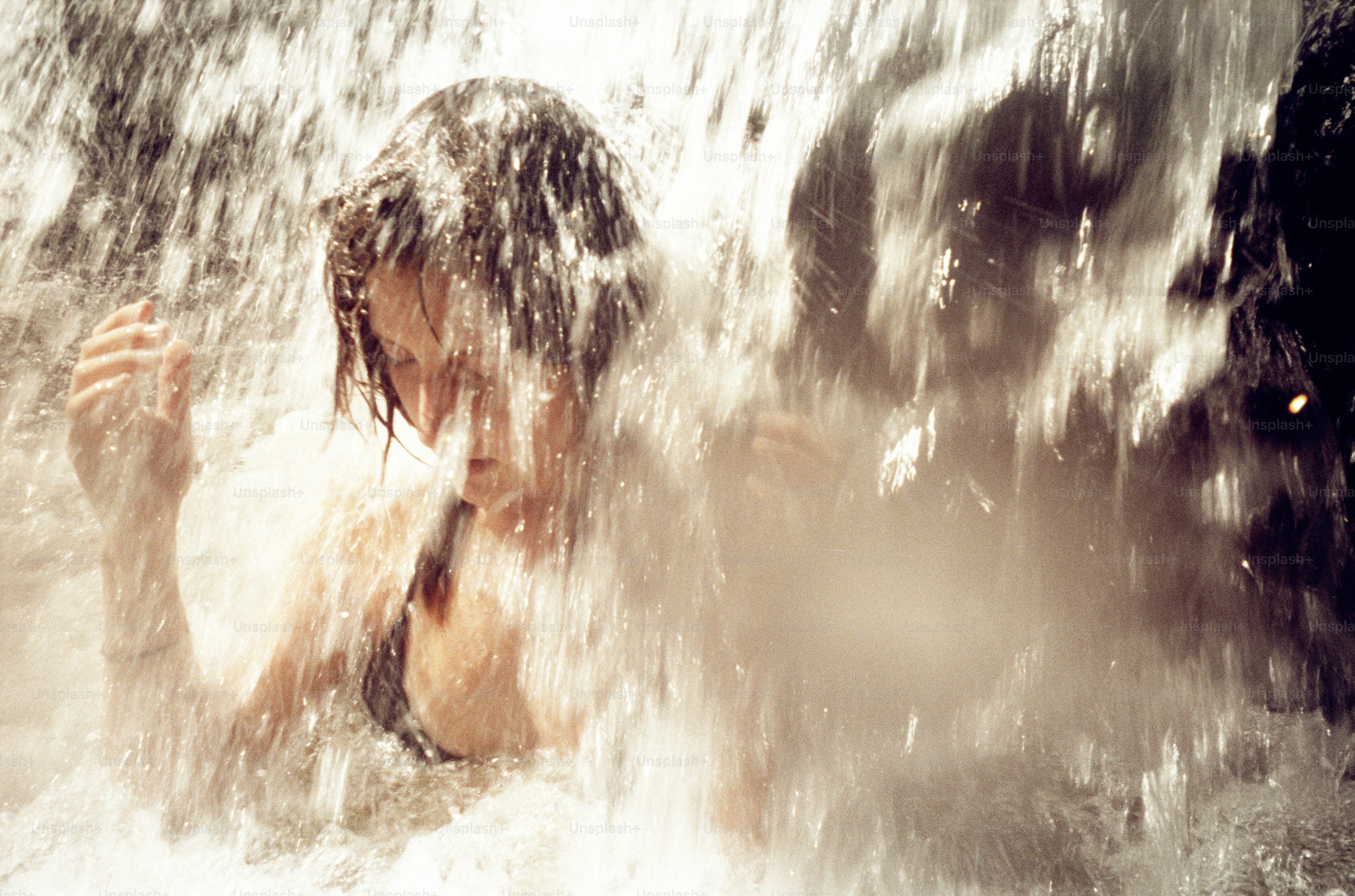 La mujer se encuentra bajo una refrescante cascada.