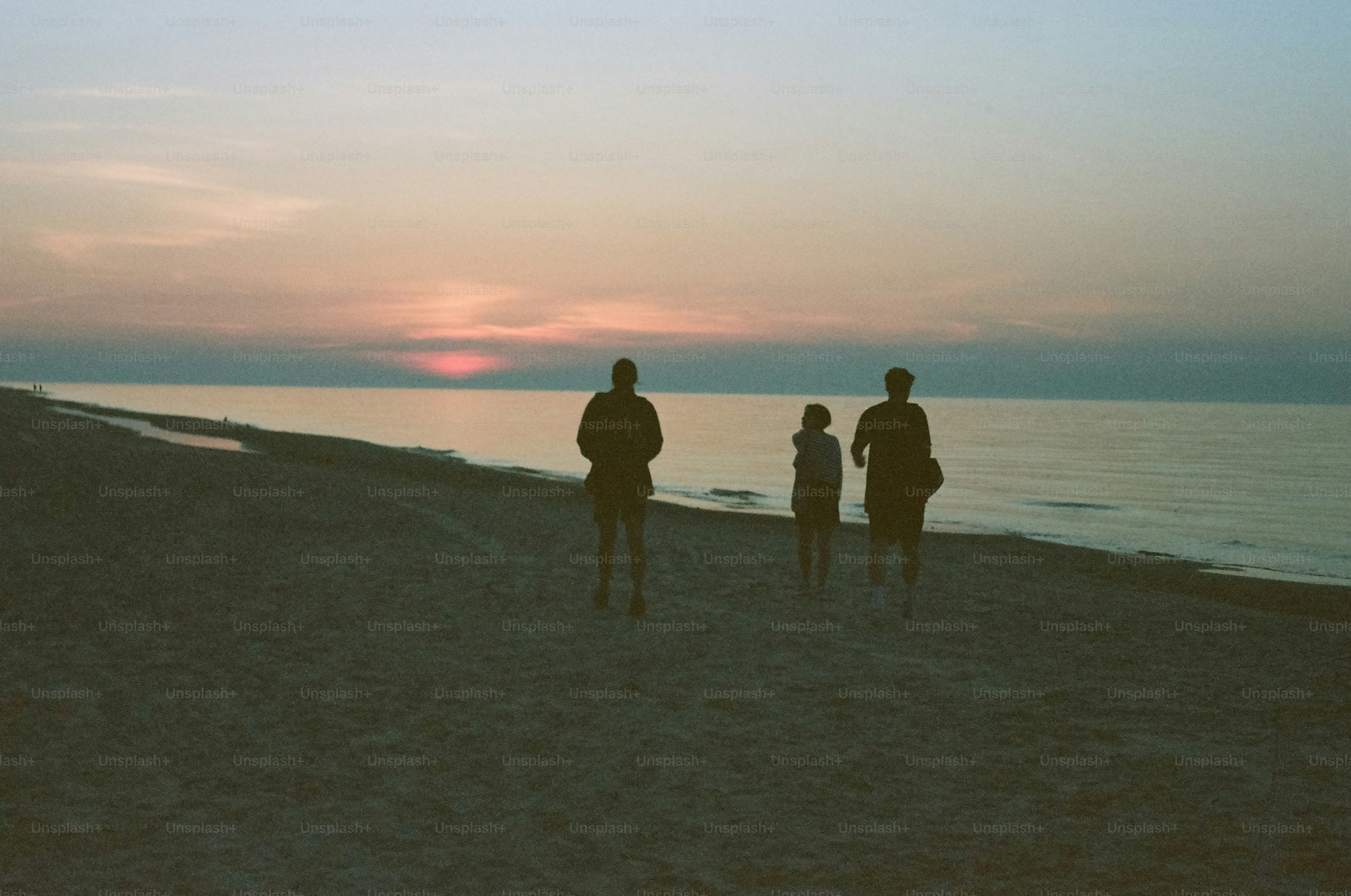 People watch the sunset on a calm beach.