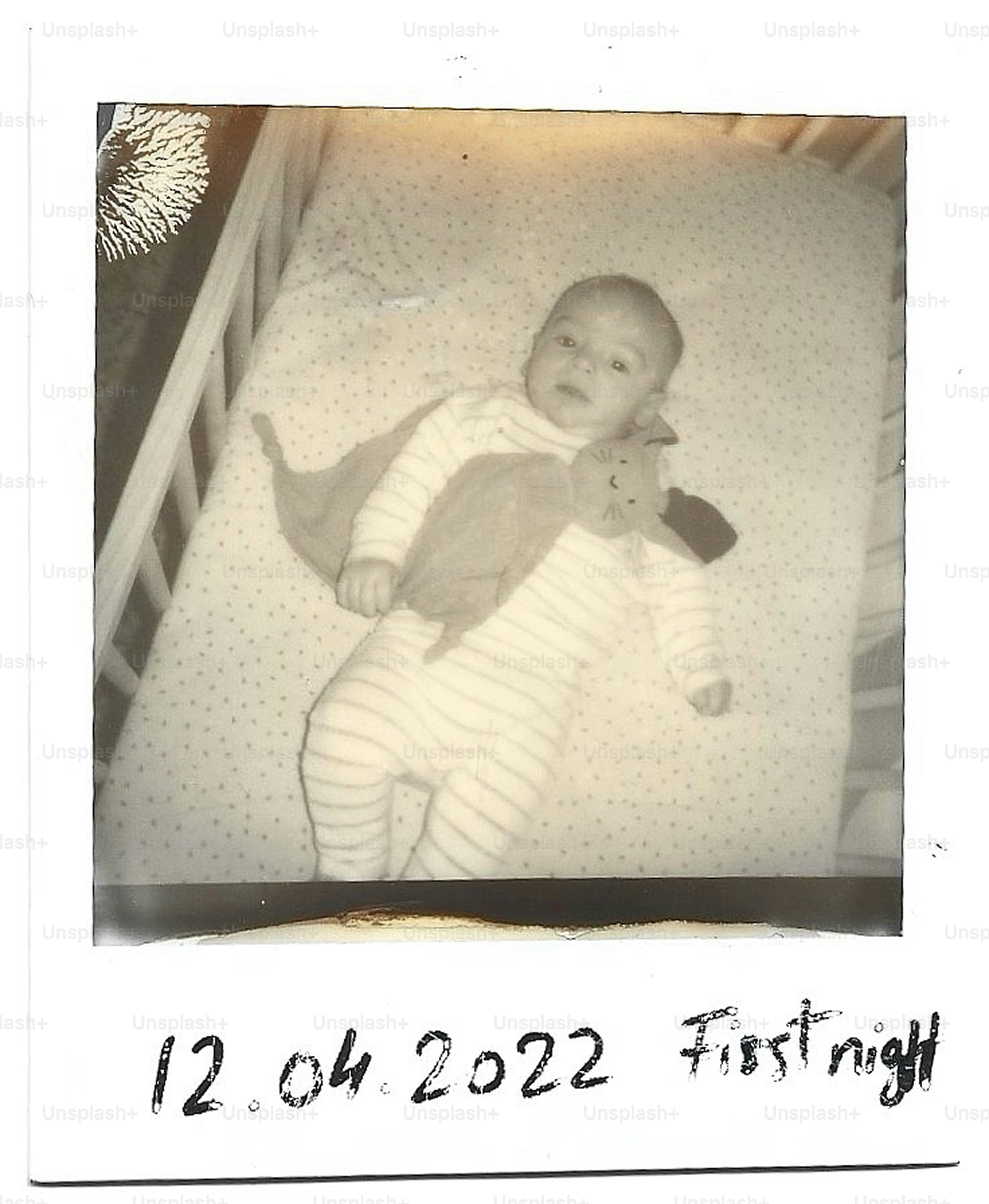 Baby lies in crib with a blanket.