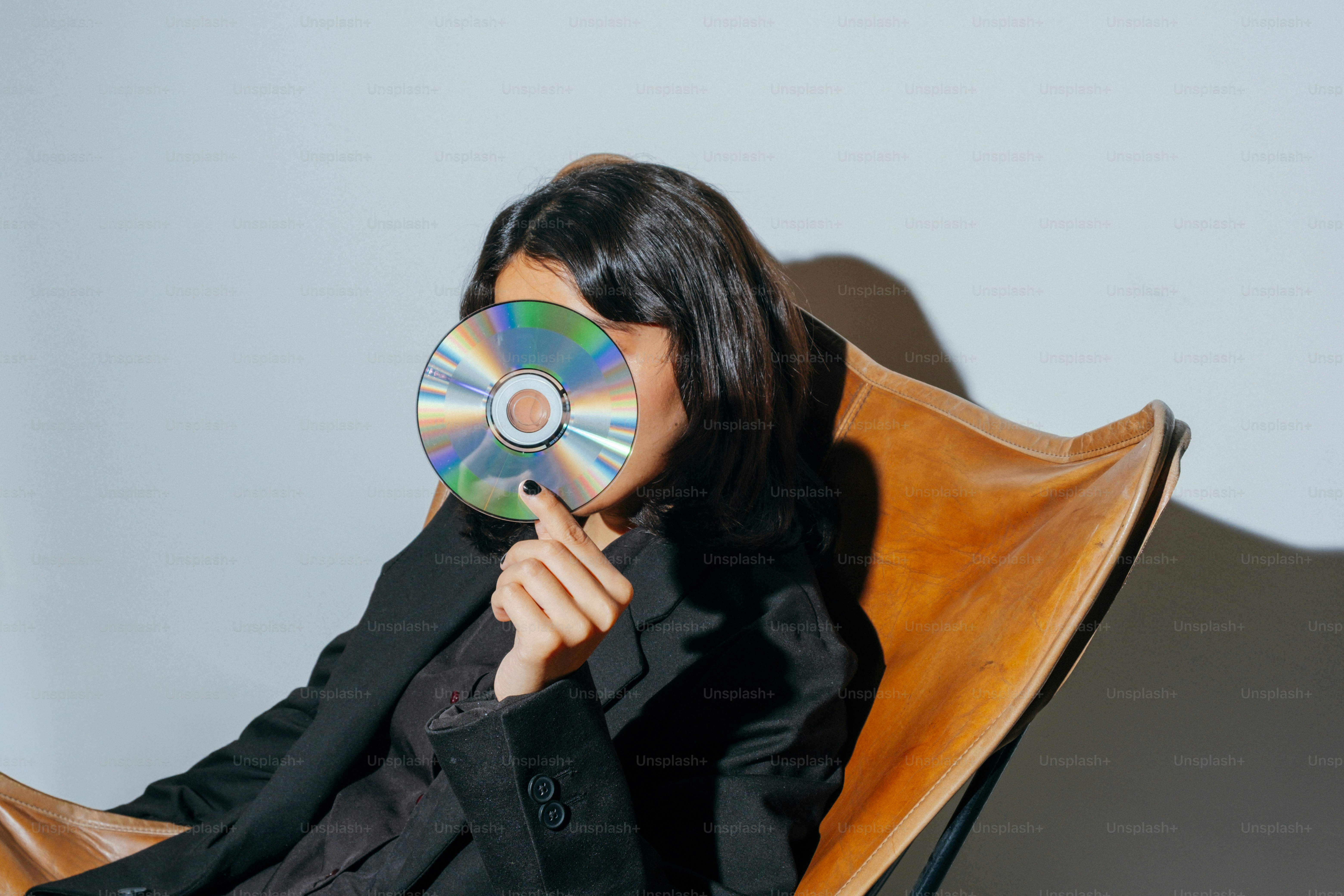 A woman covers her face with a cd.