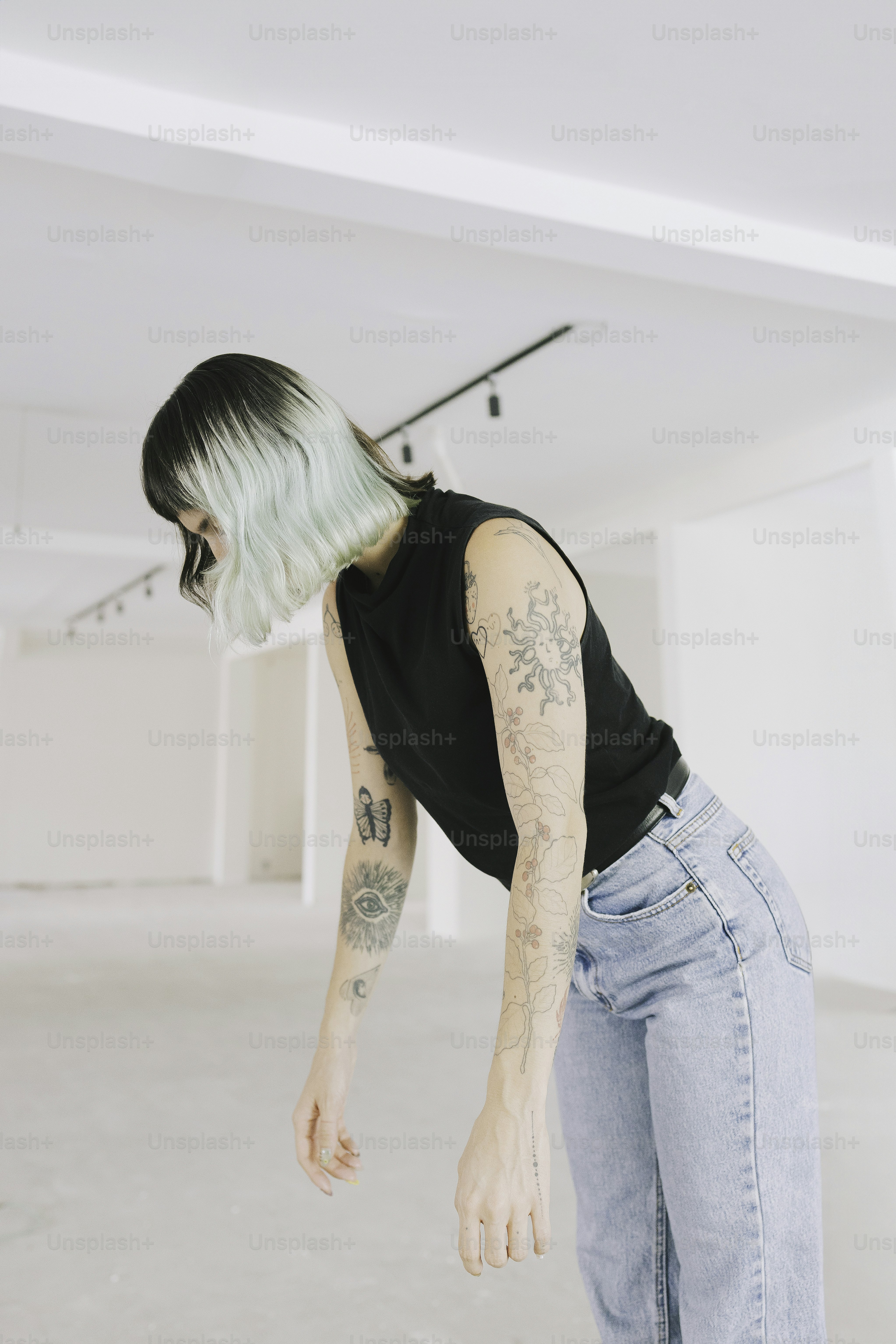 A person with tattoos stands in an empty room.