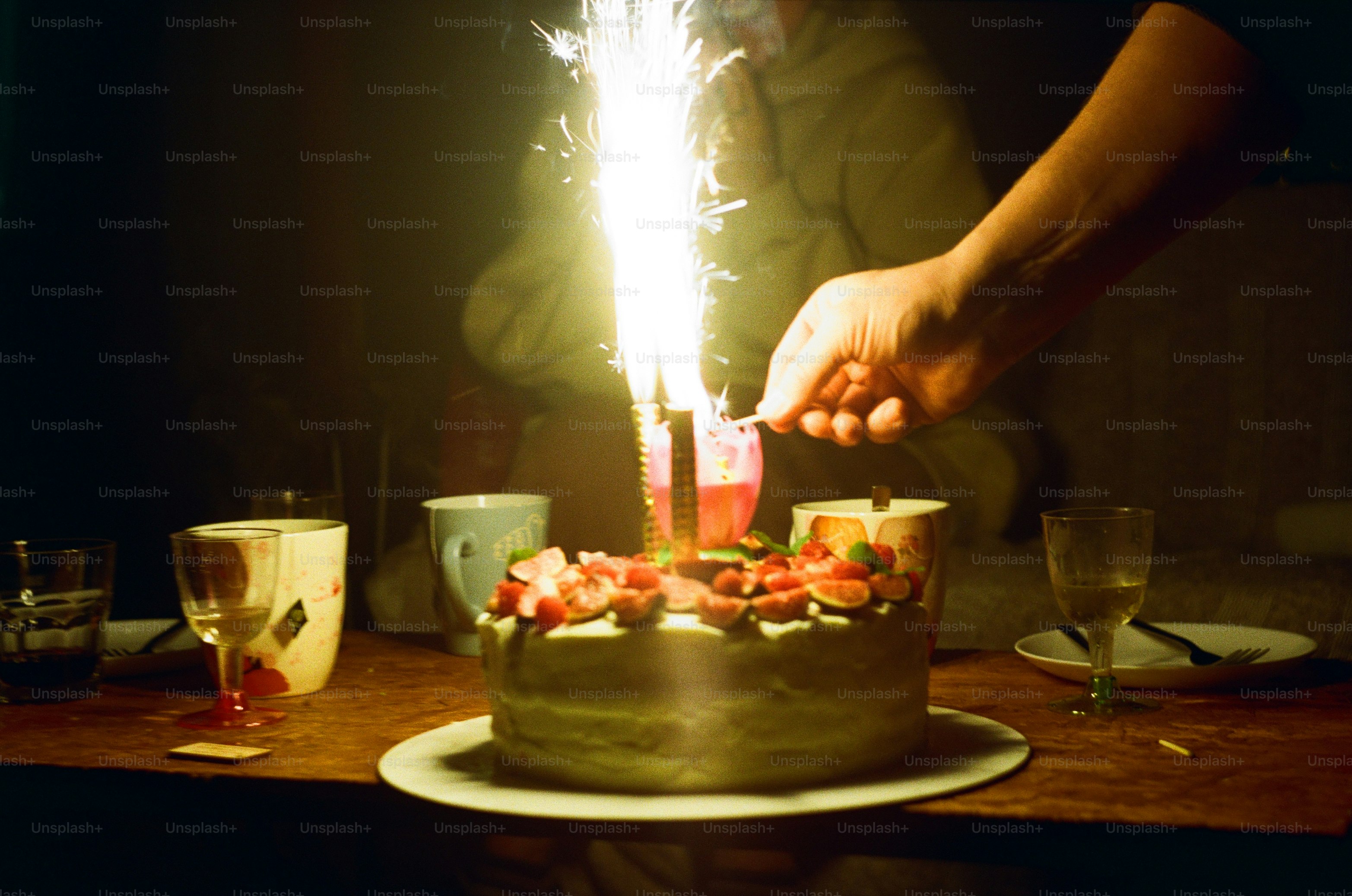 Someone lights a sparkler on a birthday cake.