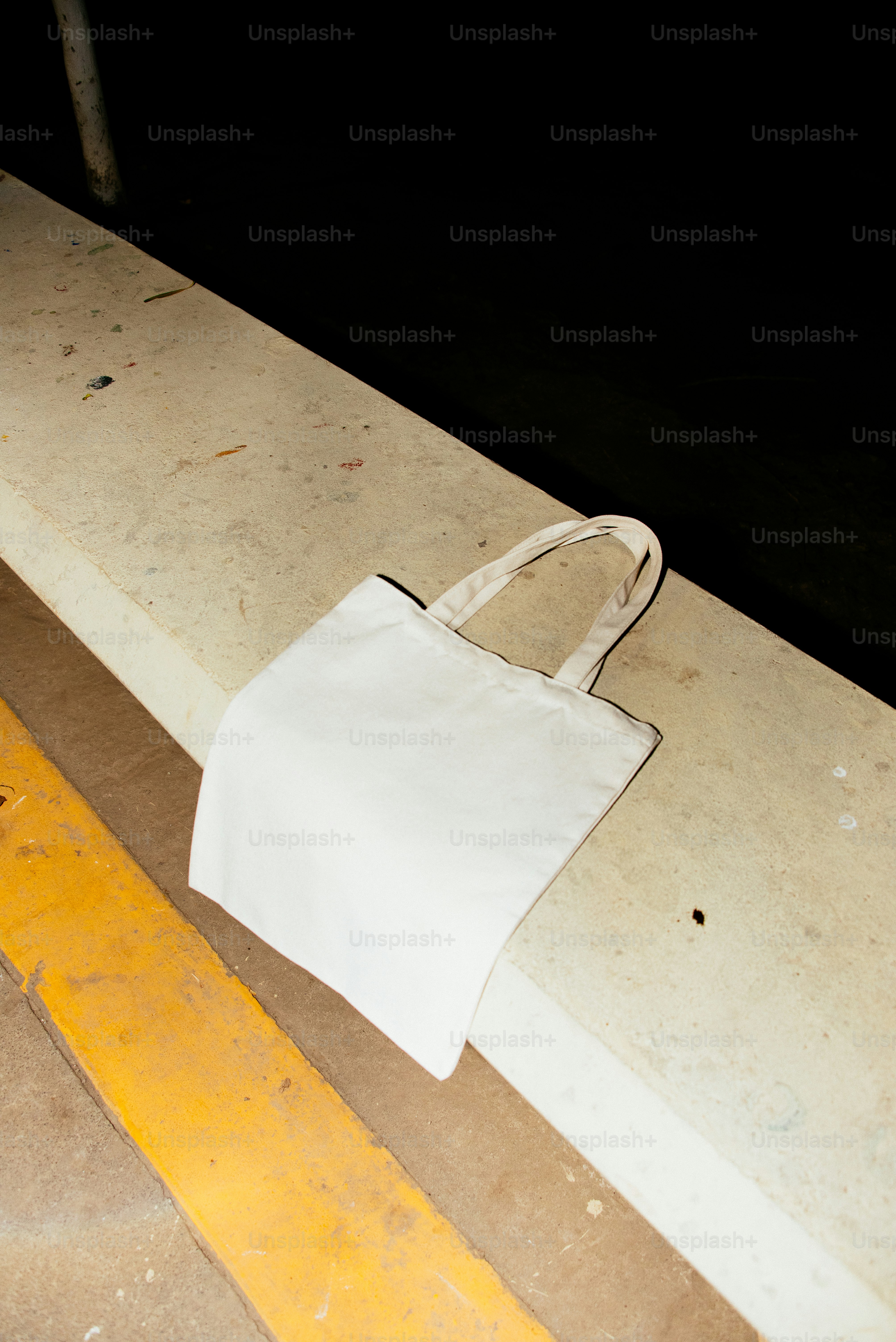 A white tote bag rests on concrete.