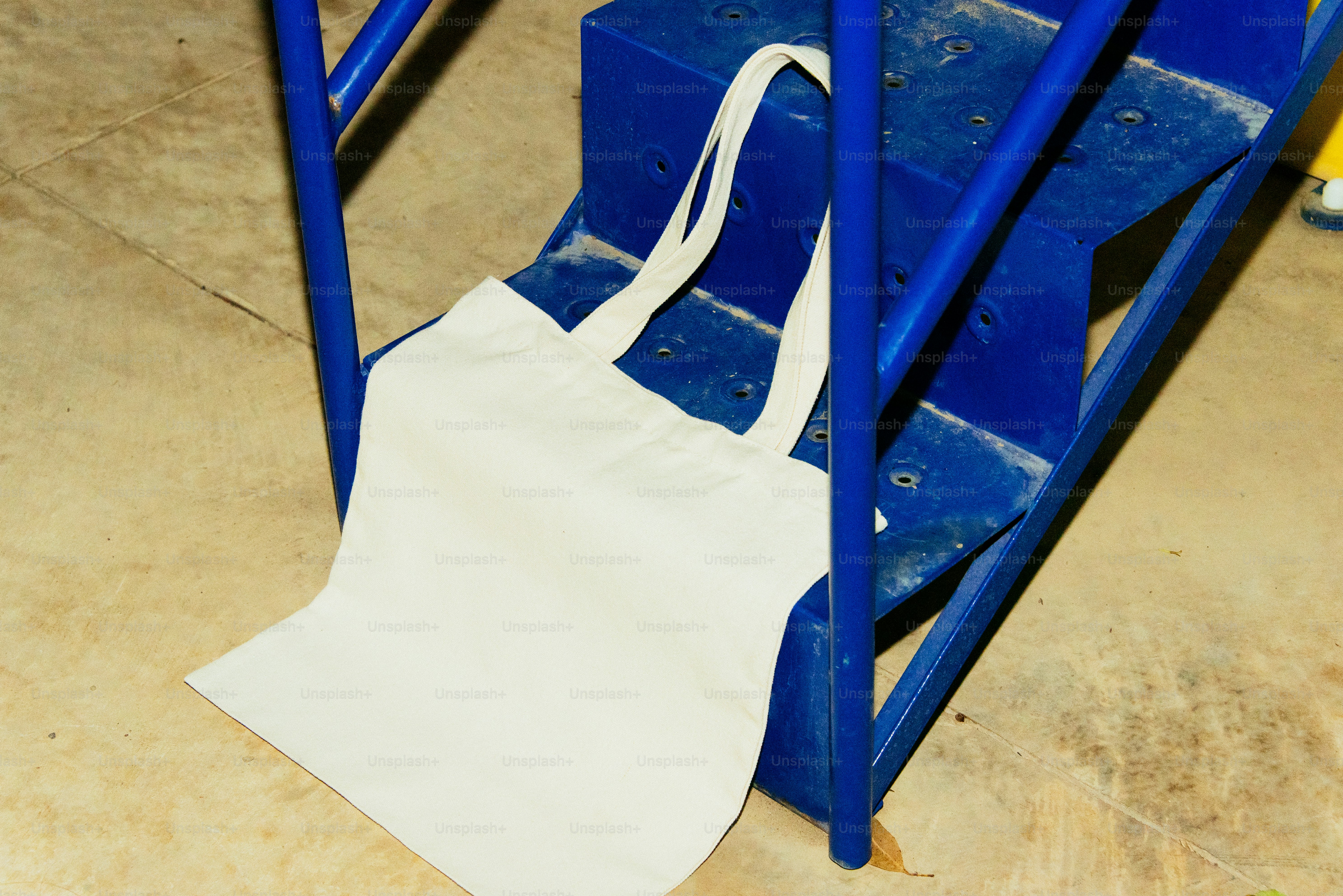 A white tote bag rests on blue steps.