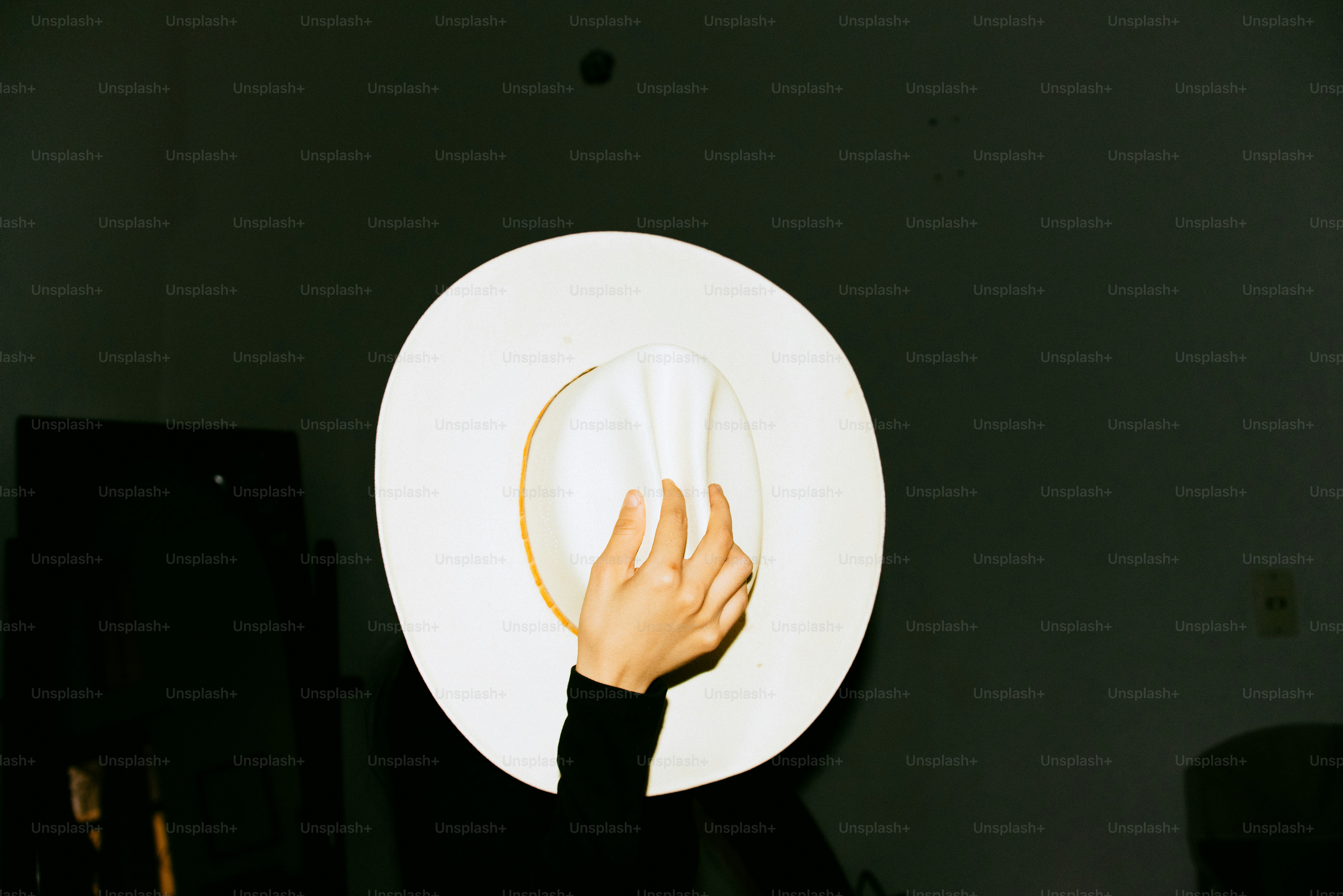 Eine Hand hält einen weißen Cowboyhut.