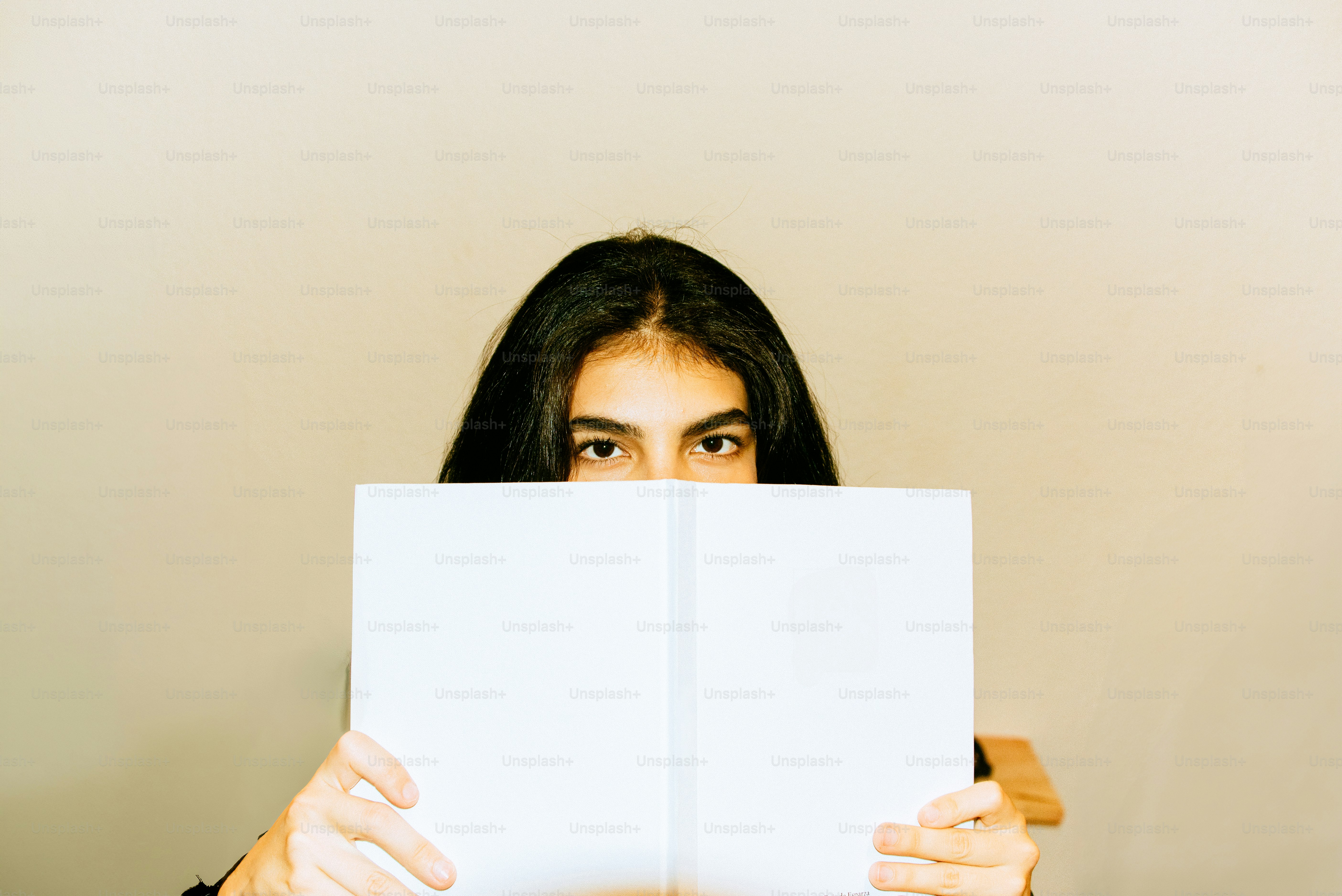 Woman peeks over a book.