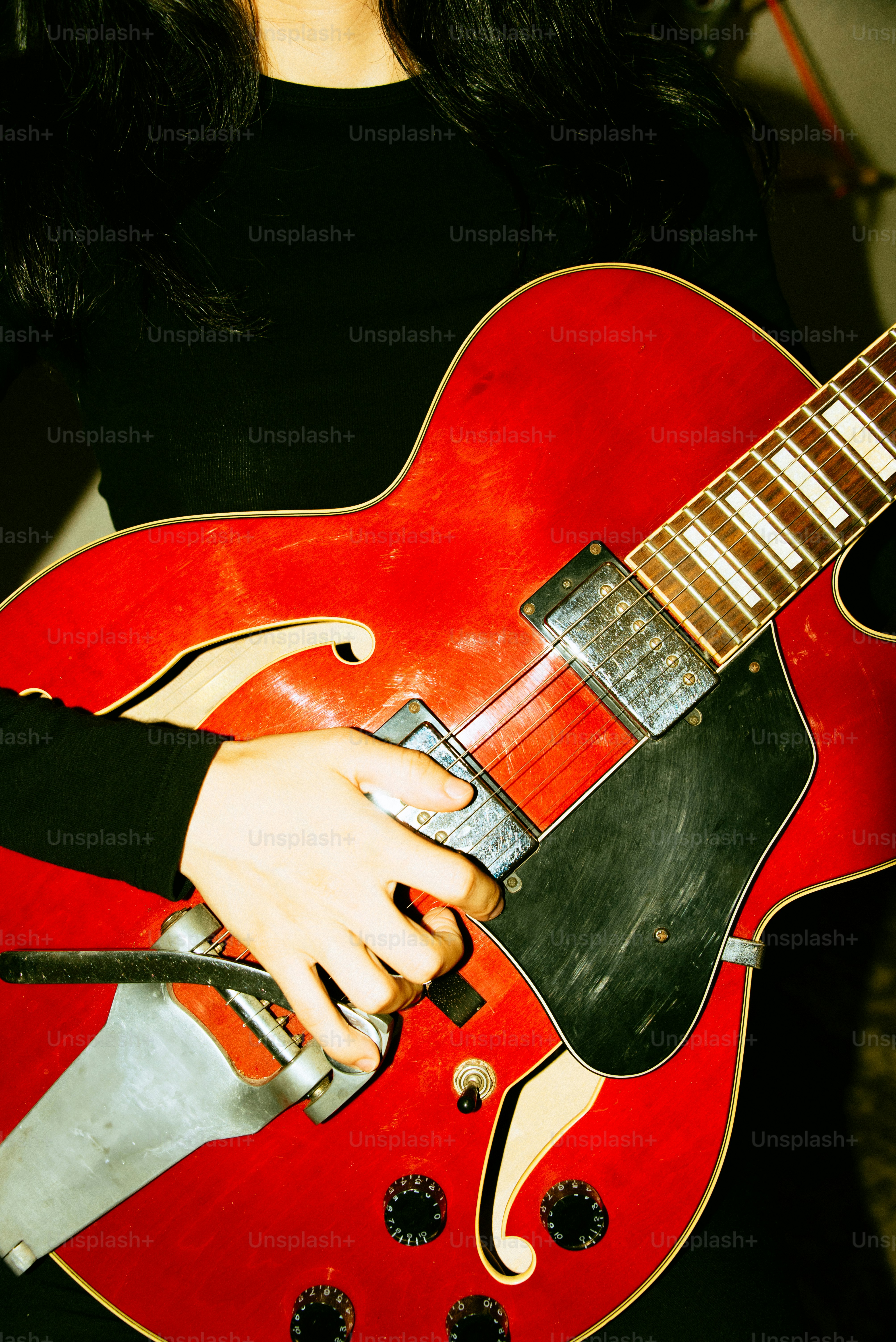 A person plays a red electric guitar.