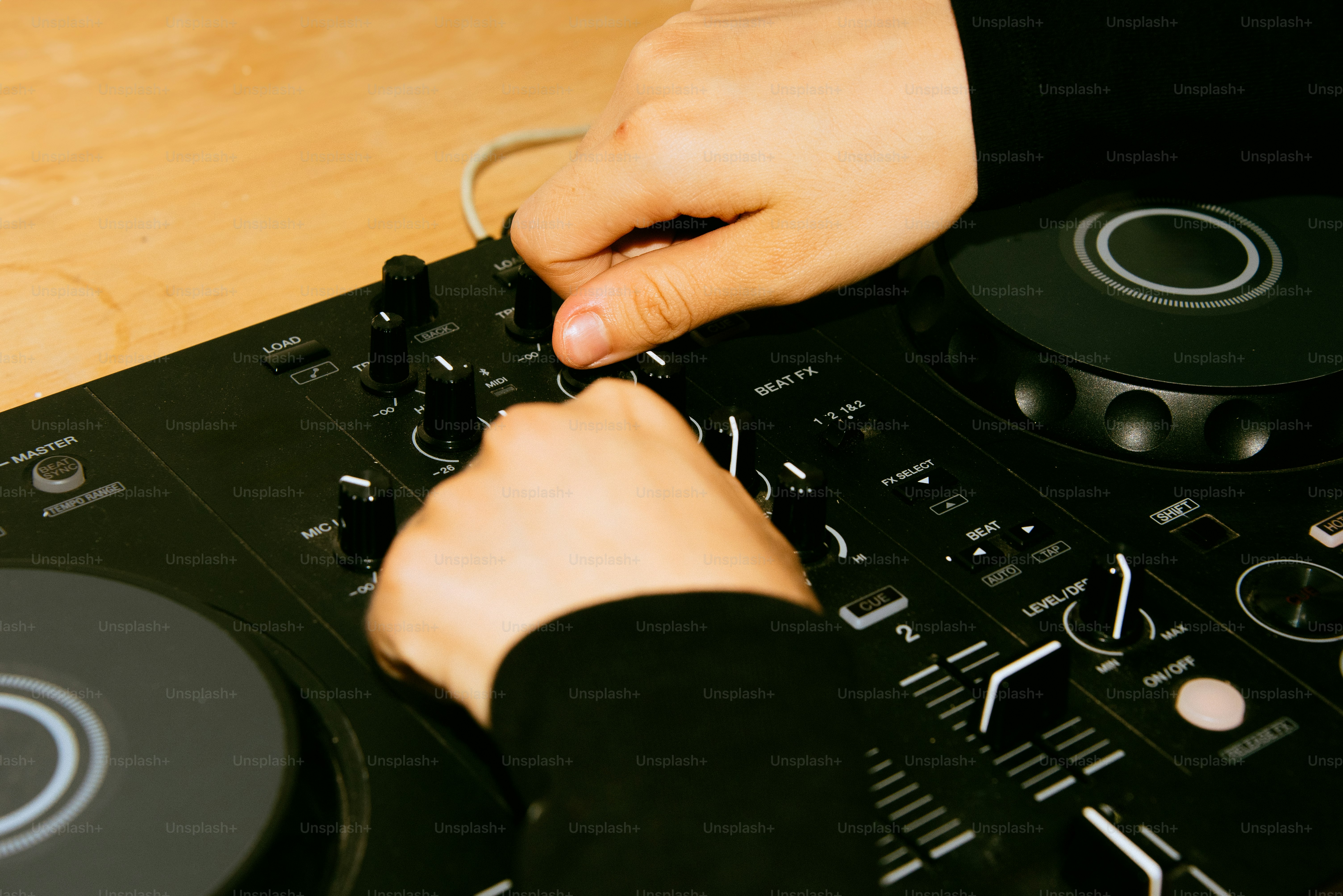Hands of a dj adjusting a mixing console.