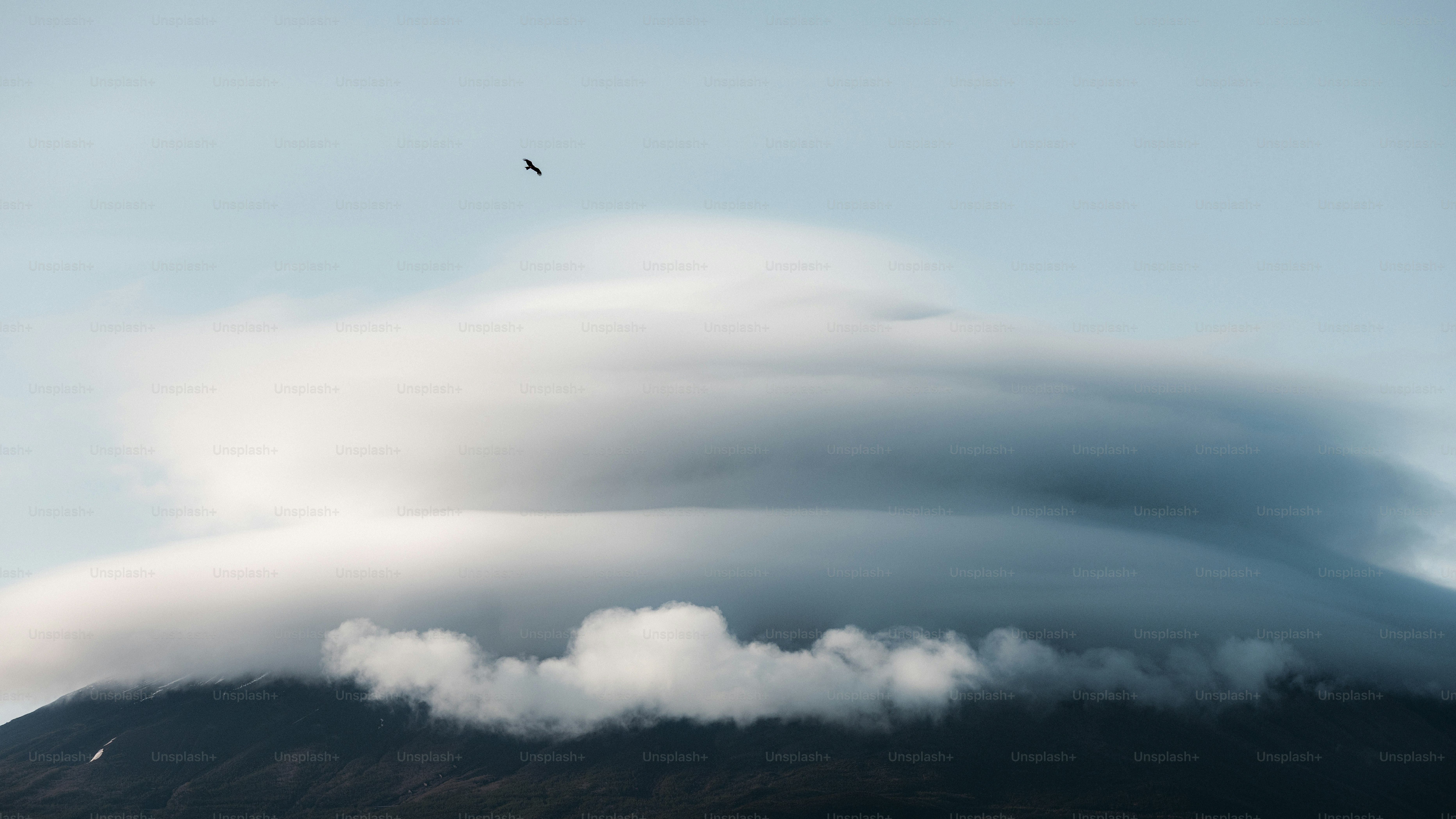 A lenticular cloud hovers over a mountain.