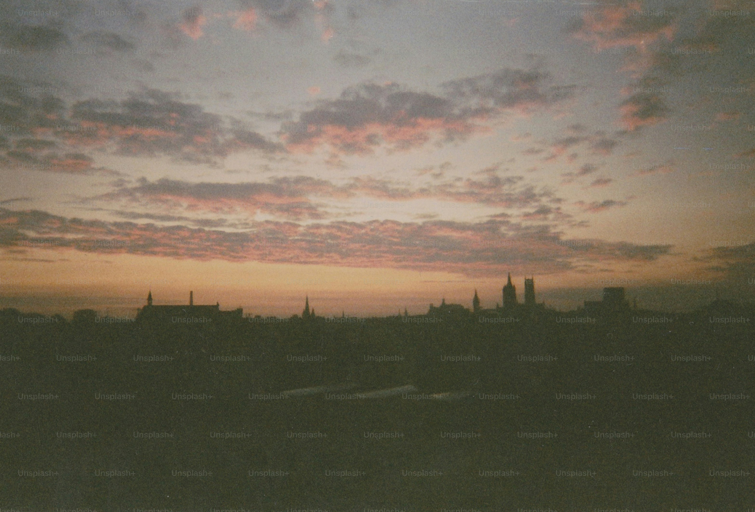 Nubes rosadas sobre la silueta de la ciudad al atardecer.