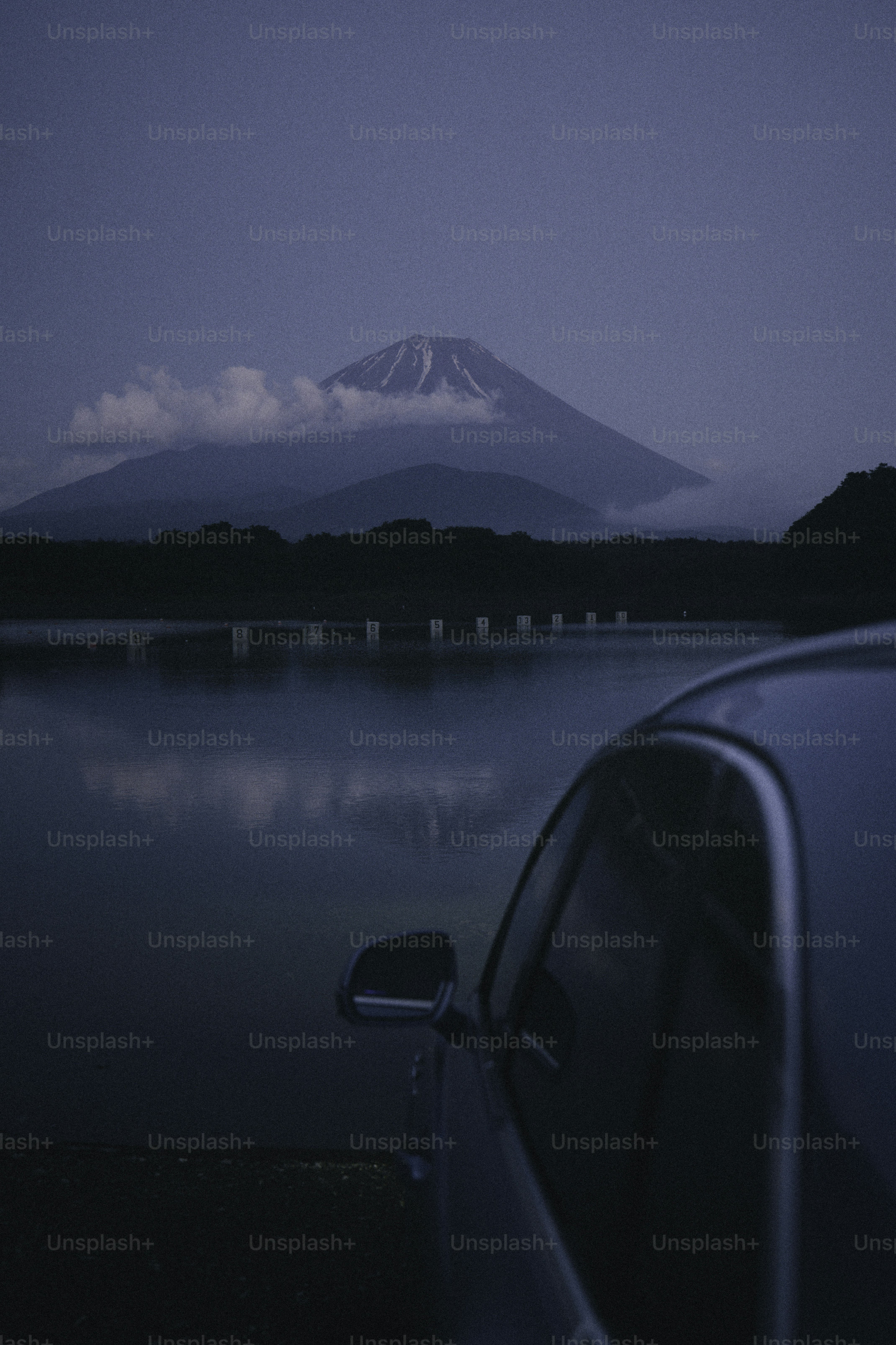 Car parked by a lake with a mountain view.