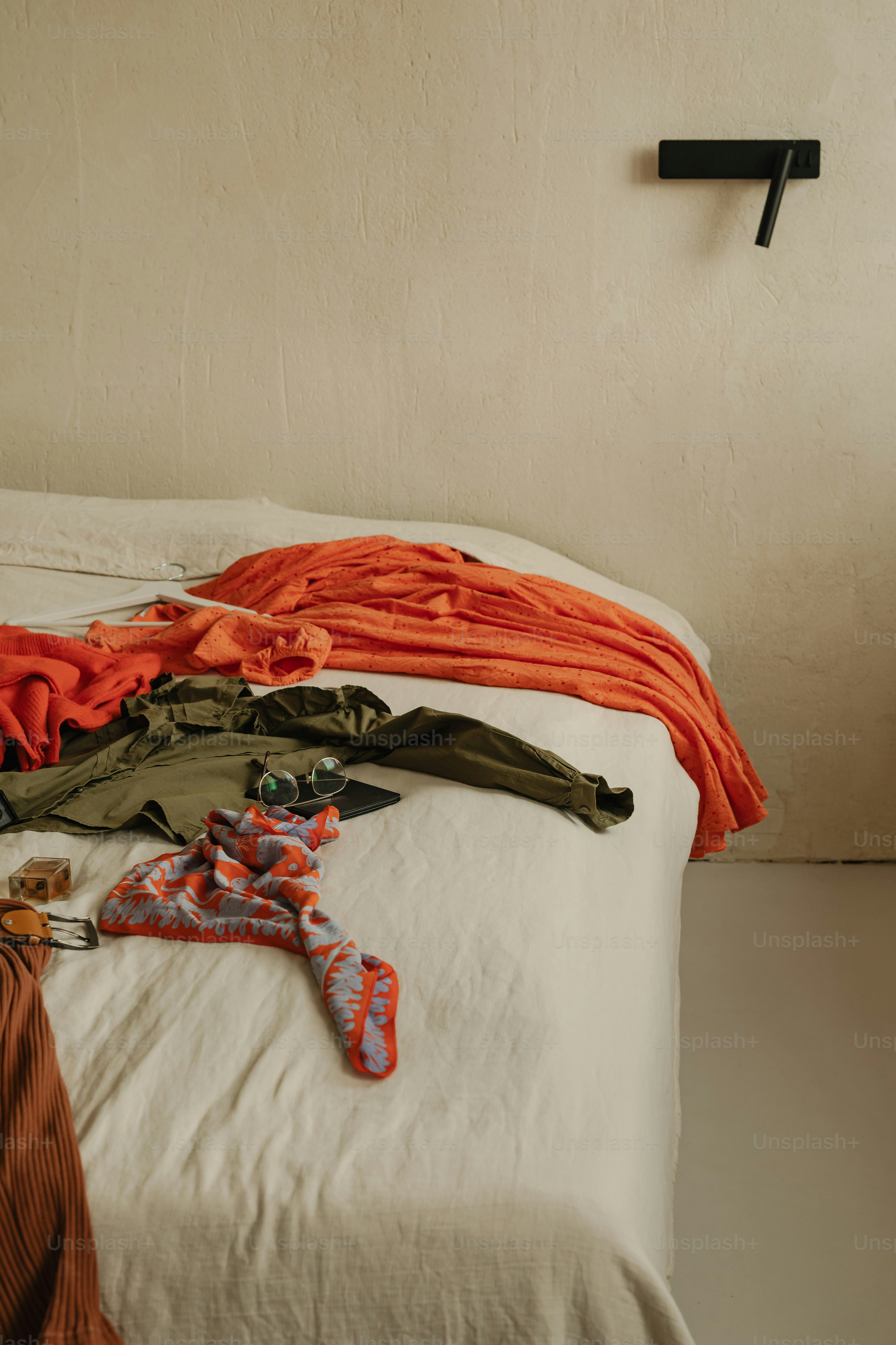 Clothes are strewn across a messy bed.