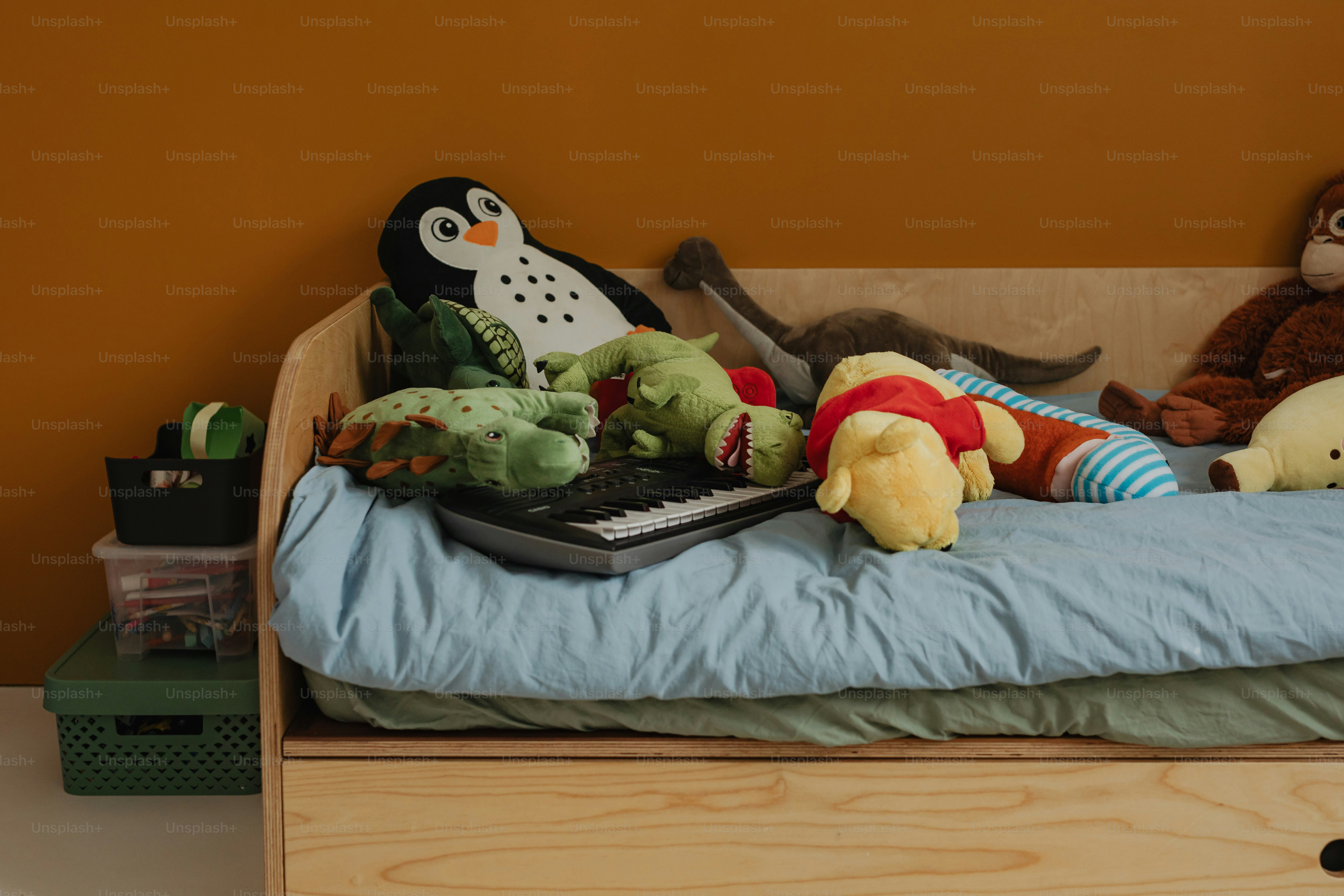 Bed covered in stuffed animals and a piano.