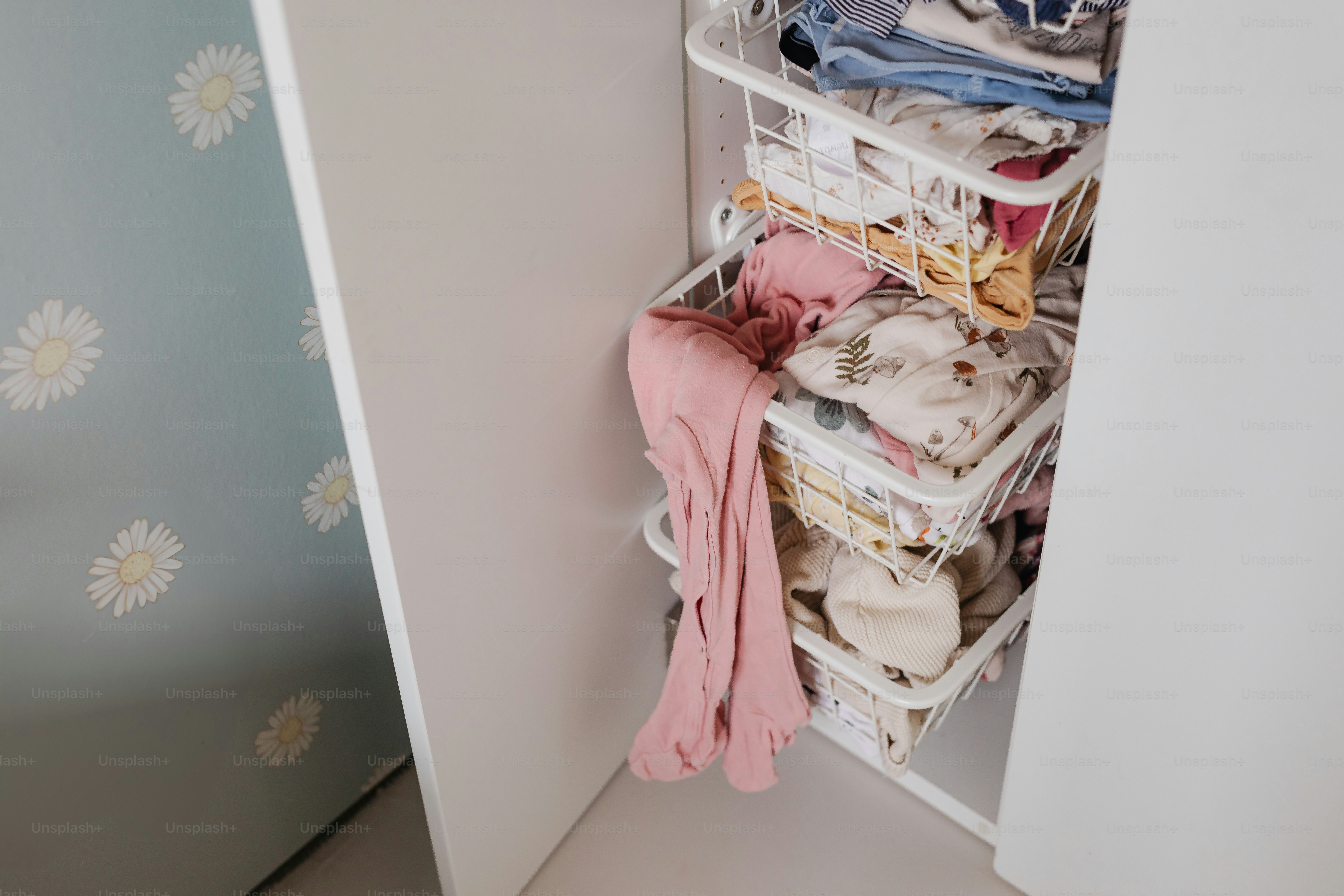 Baby clothes organized in wire baskets.