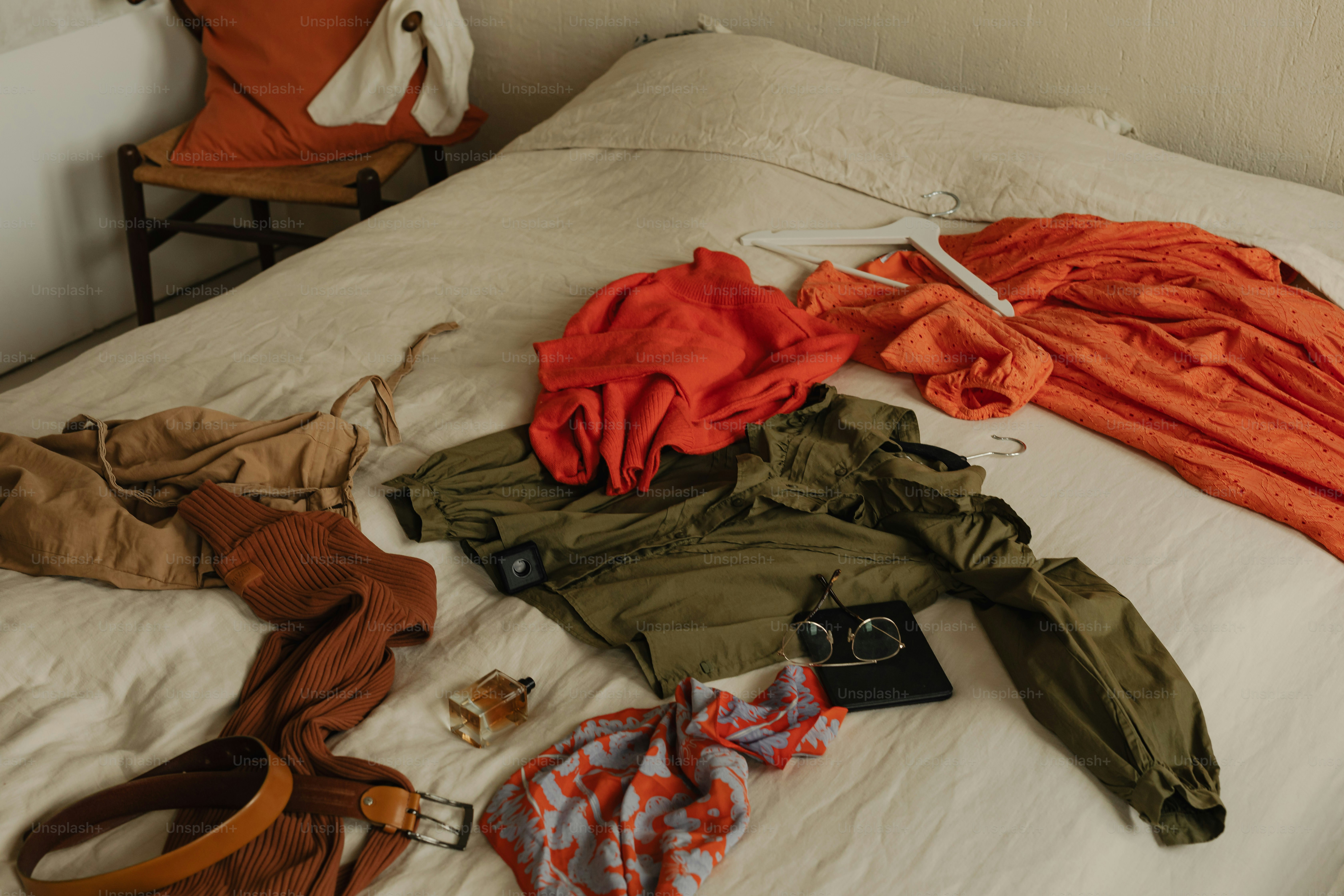 Clothes are scattered on a messy bed.
