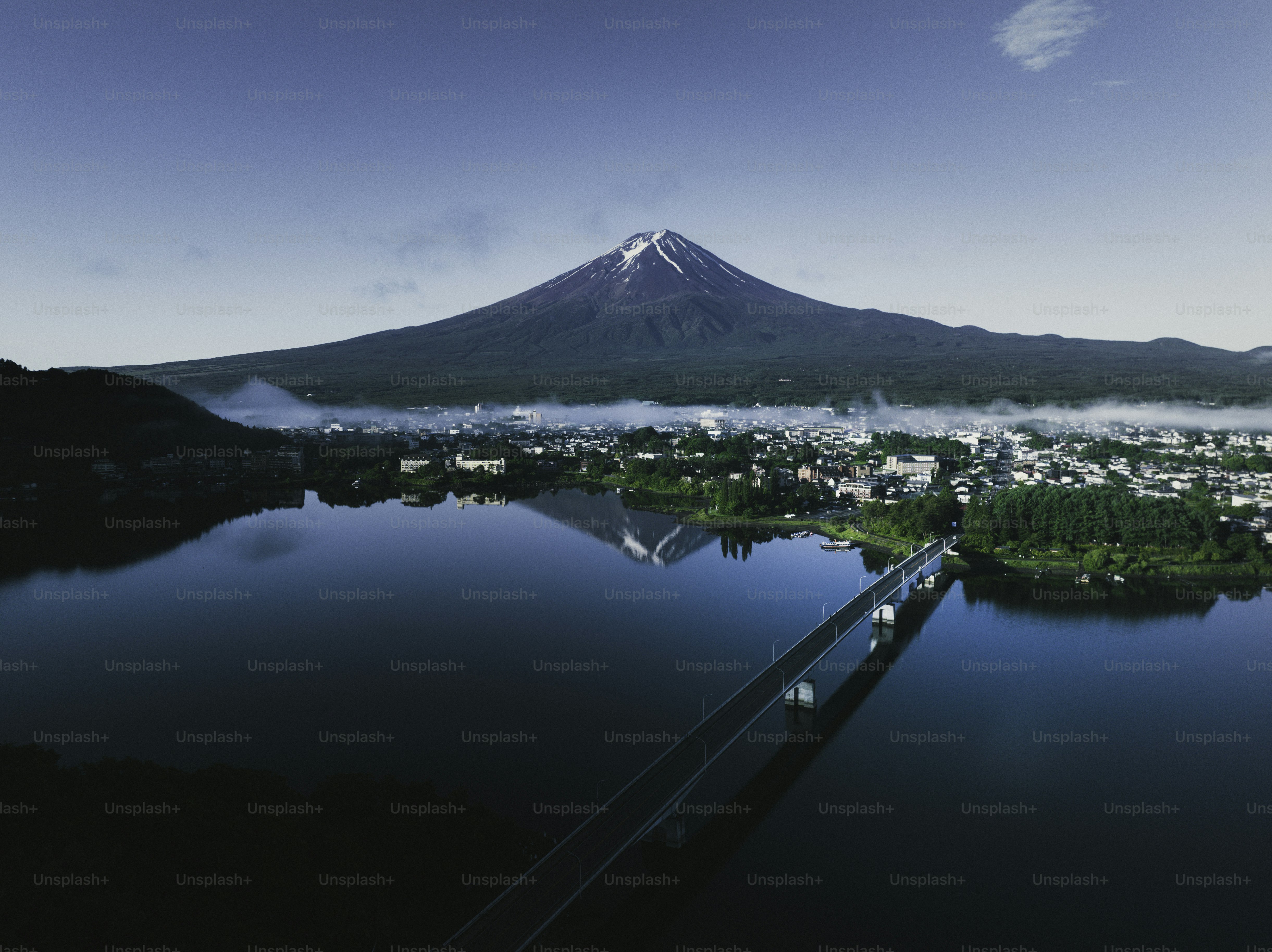 Mount fuji looms over a serene lake and town.