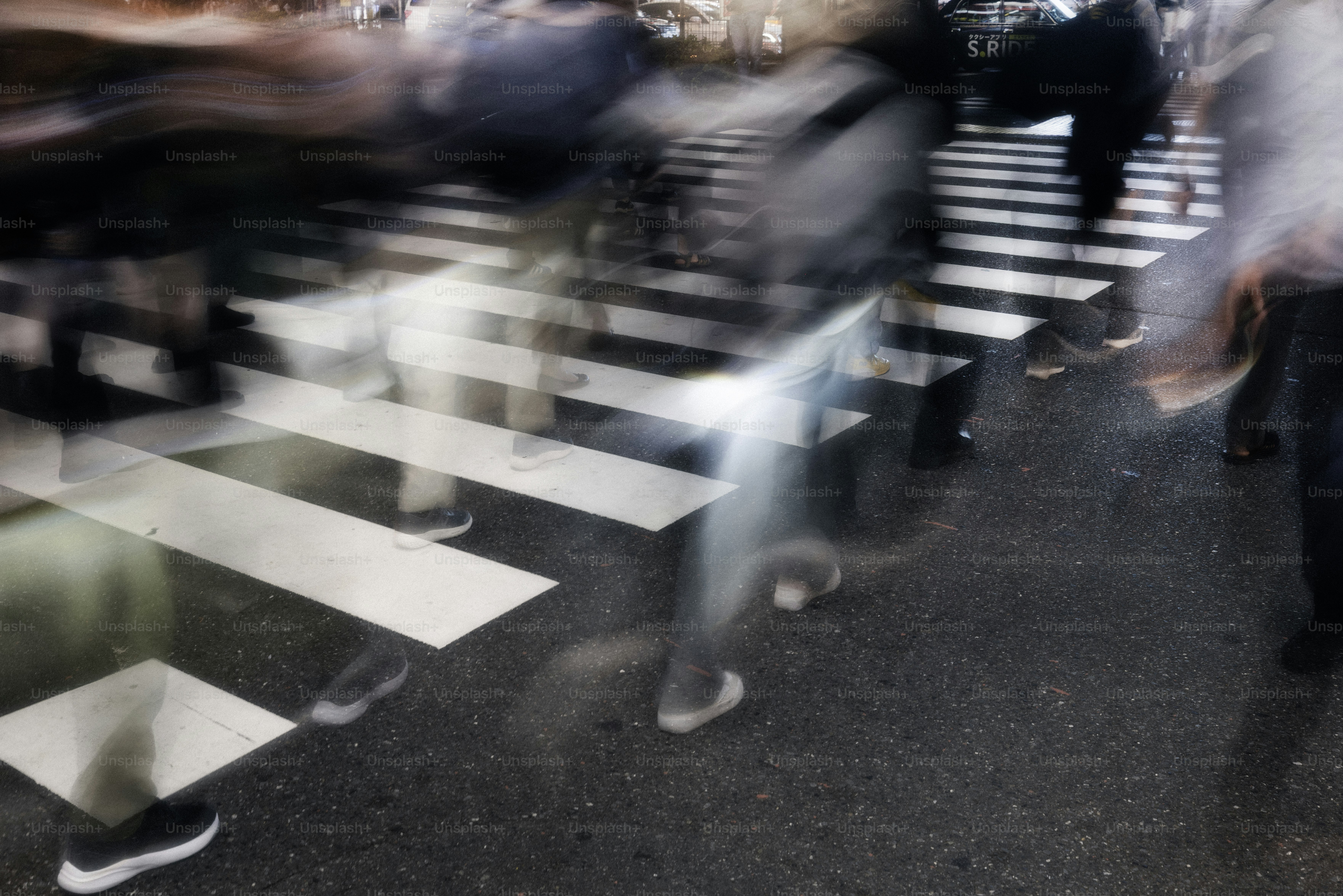People are blurred as they cross a busy street.