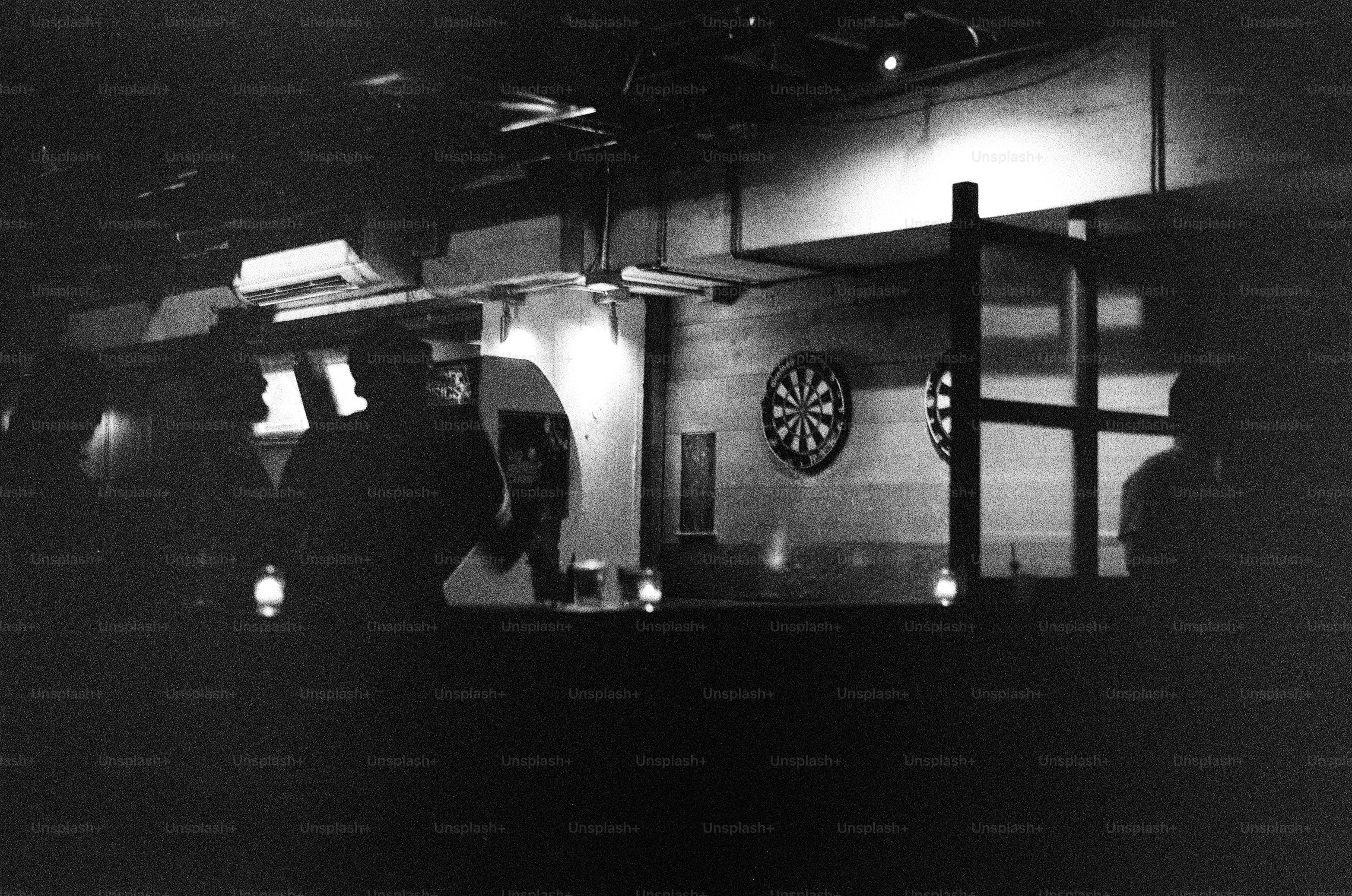 As pessoas estão jogando dardos em um bar mal iluminado