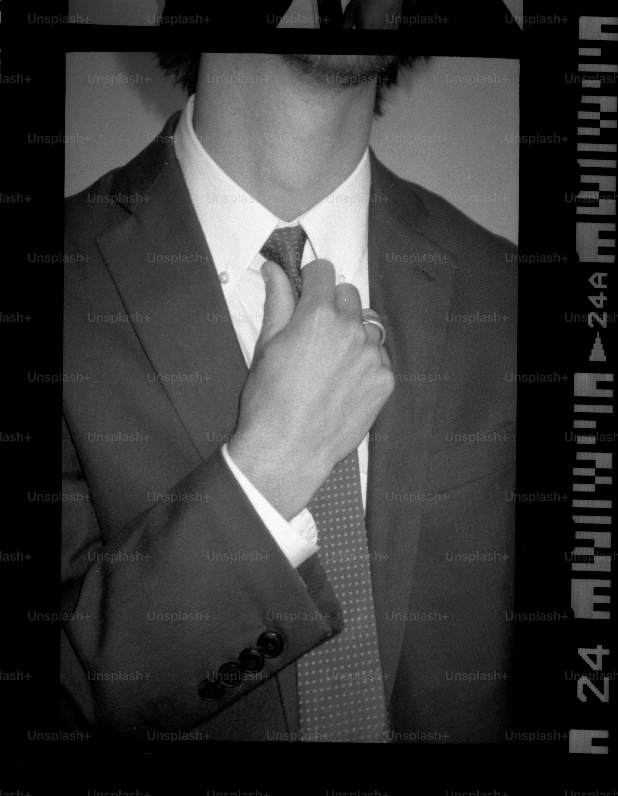 Man adjusts his tie, dressed in a suit. photo – Abstract Image on Unsplash