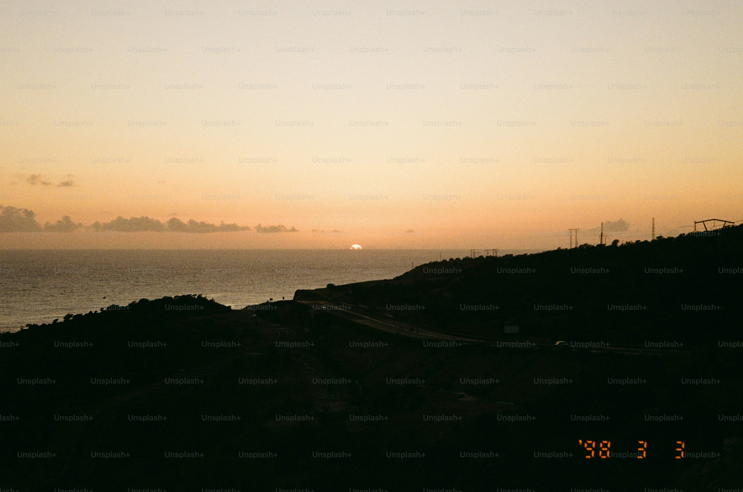 Sunset over the ocean with a winding road.