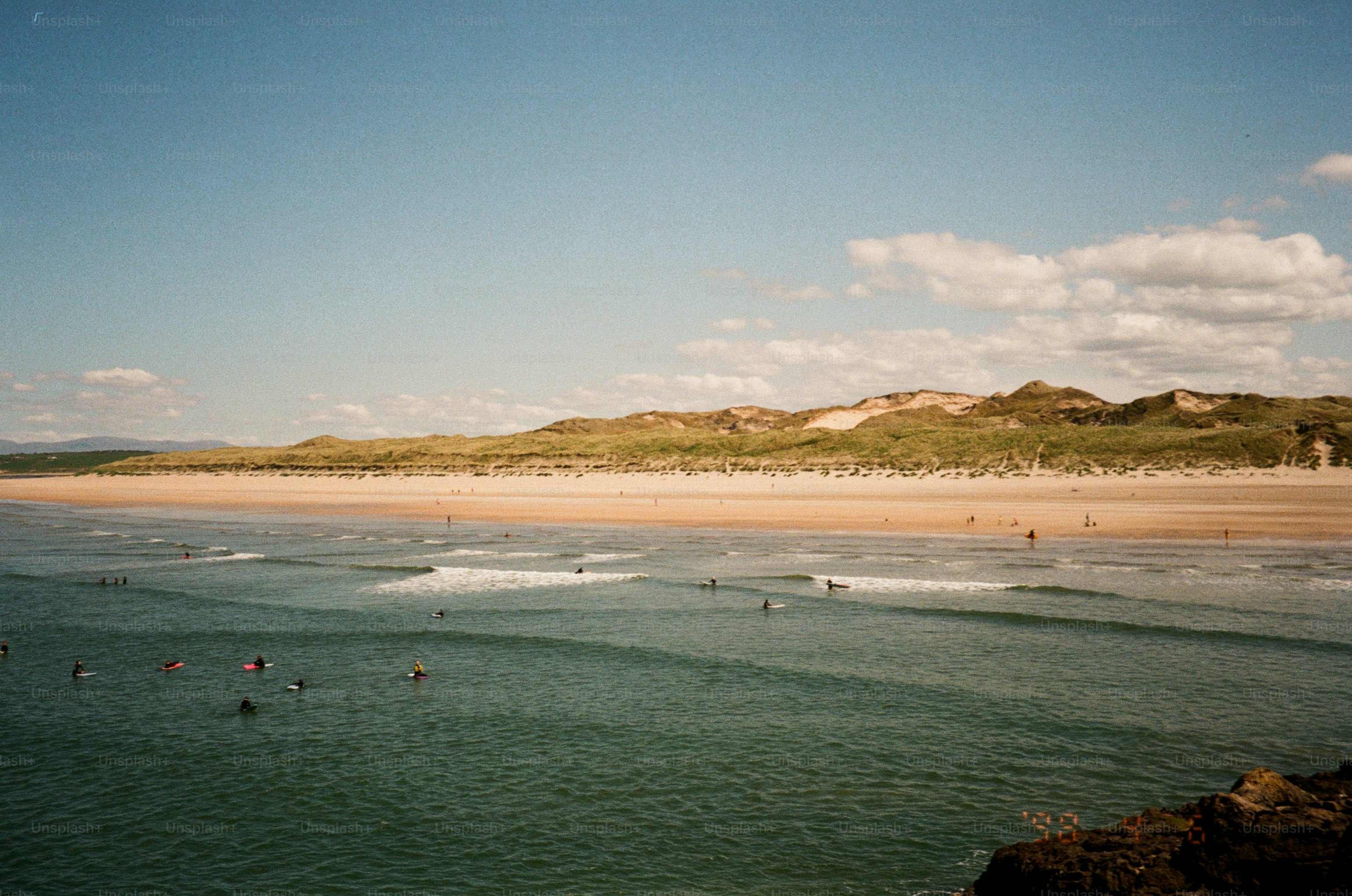 A scenic beach scene with surfers and dunes.