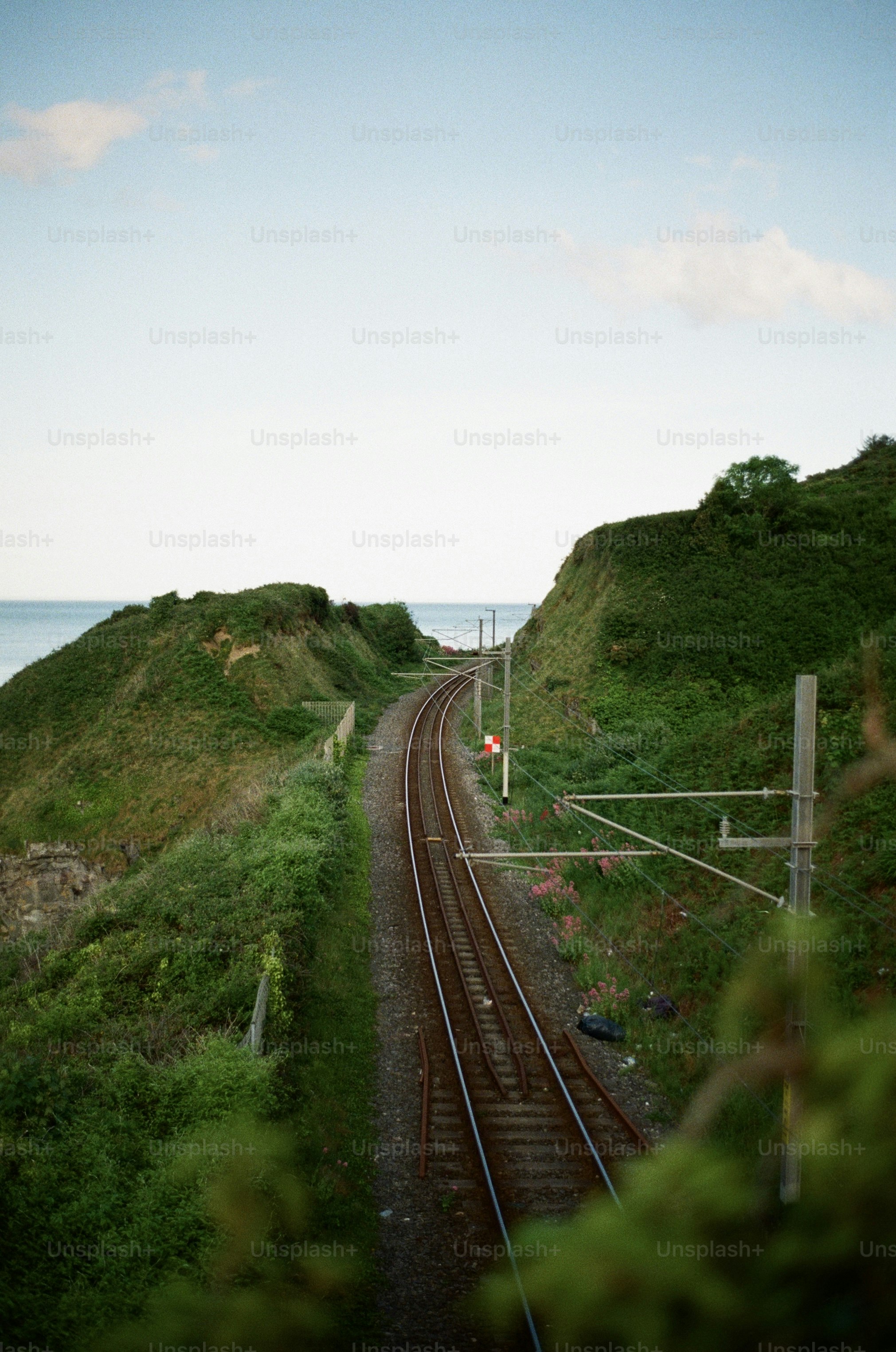 Train tracks curve along a green cliffside.