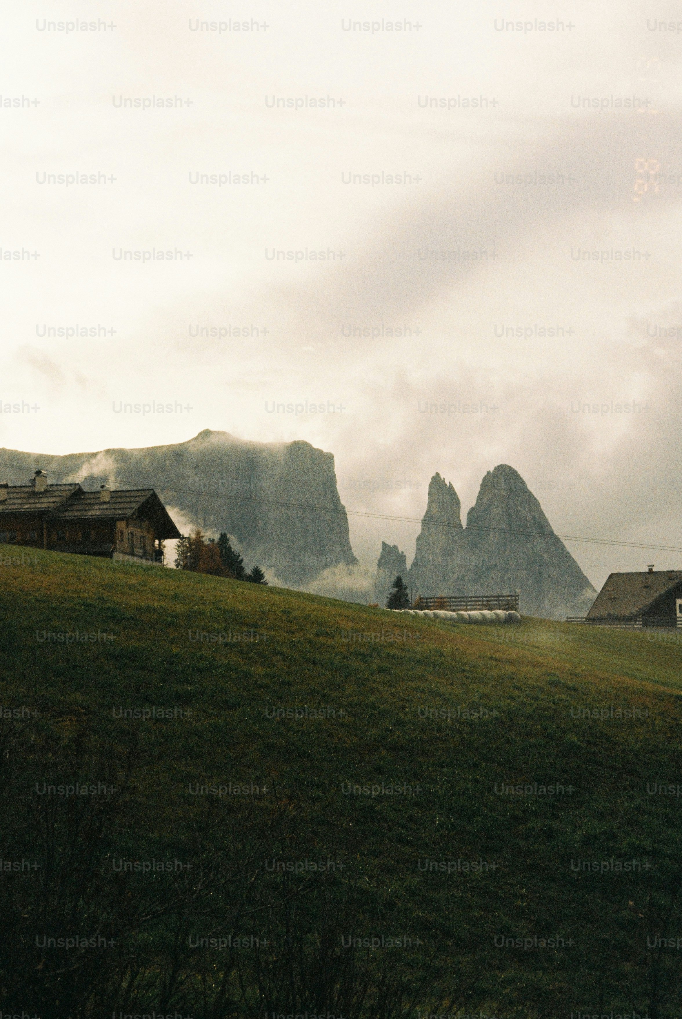 Mountains loom over a rural landscape on a cloudy day.