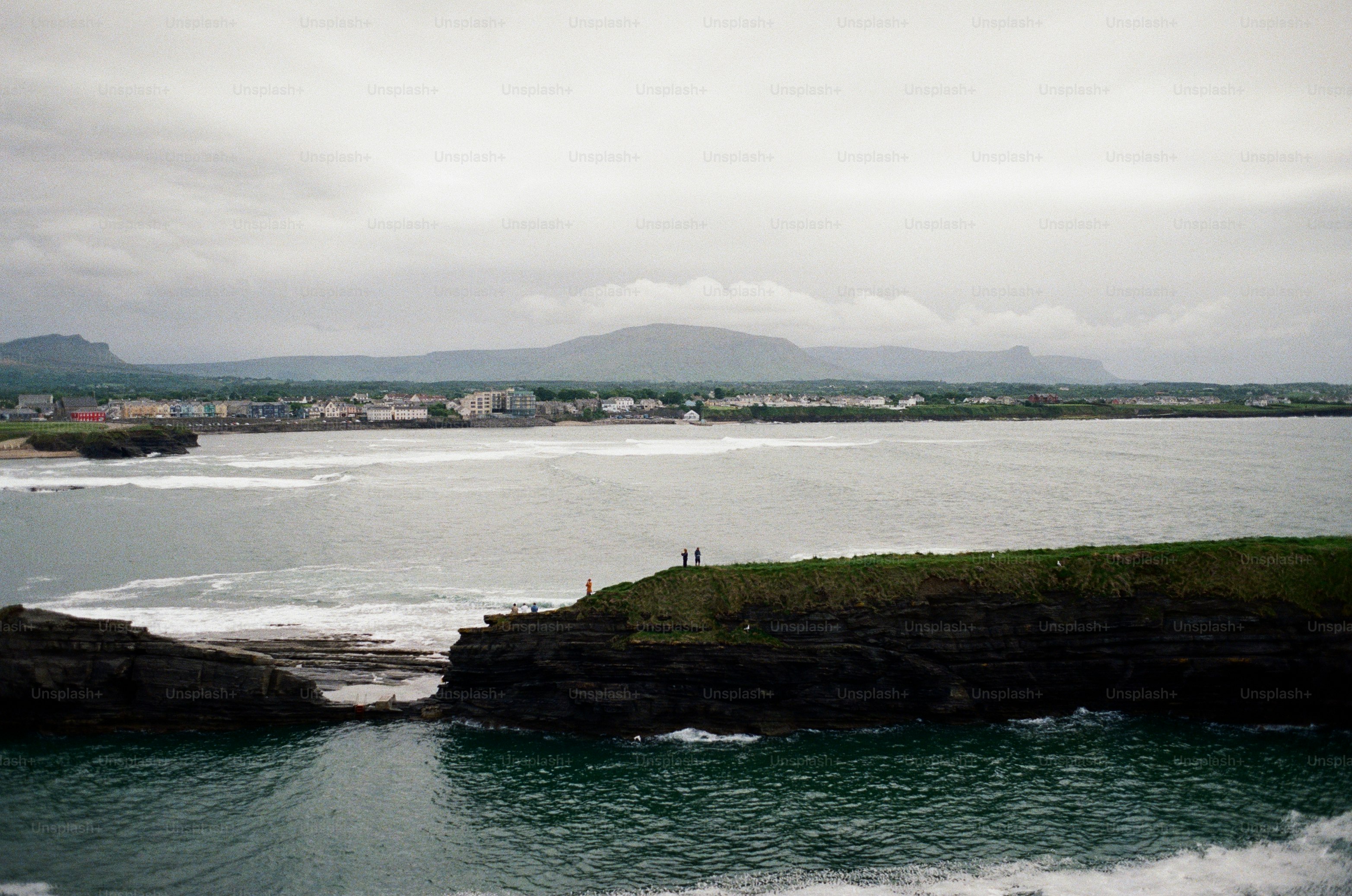 Ocean waters flow between cliffs under a cloudy sky.