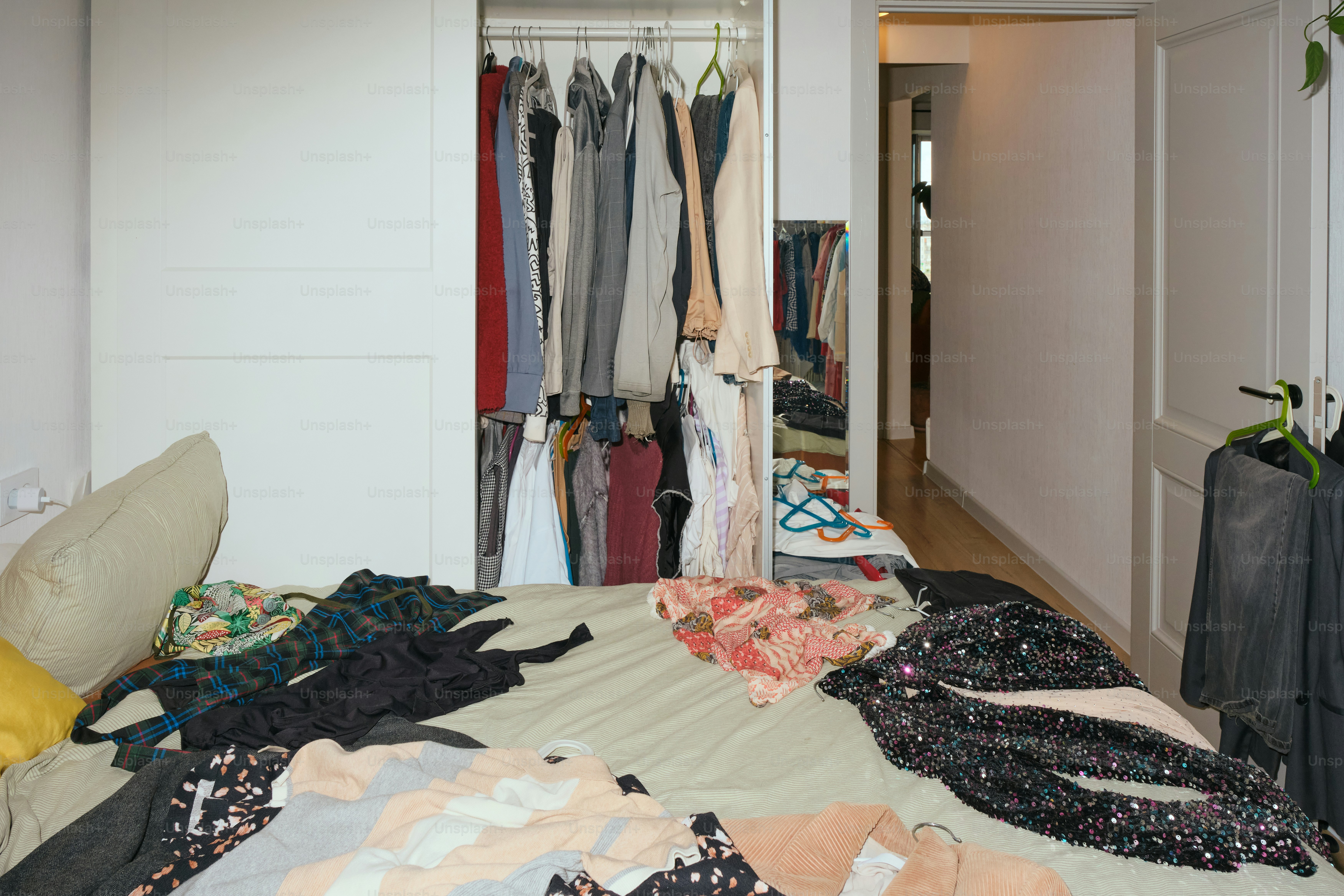 Clothes are piled on the bed, and the closet is open.