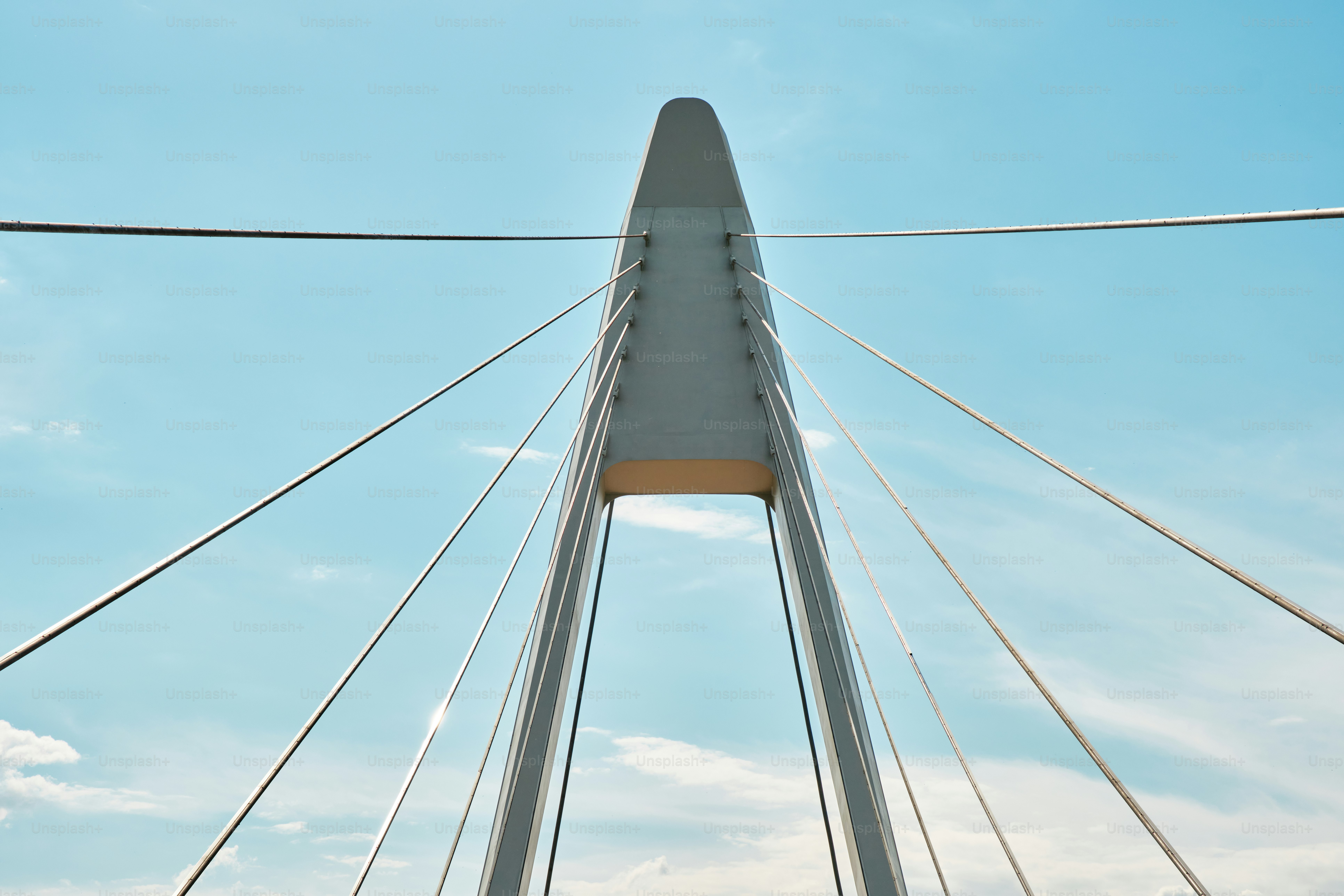 Los cables se extienden desde el pilón de un puente hacia el cielo. foto –  Imagen de Viajar en Unsplash, image size:3000x2000