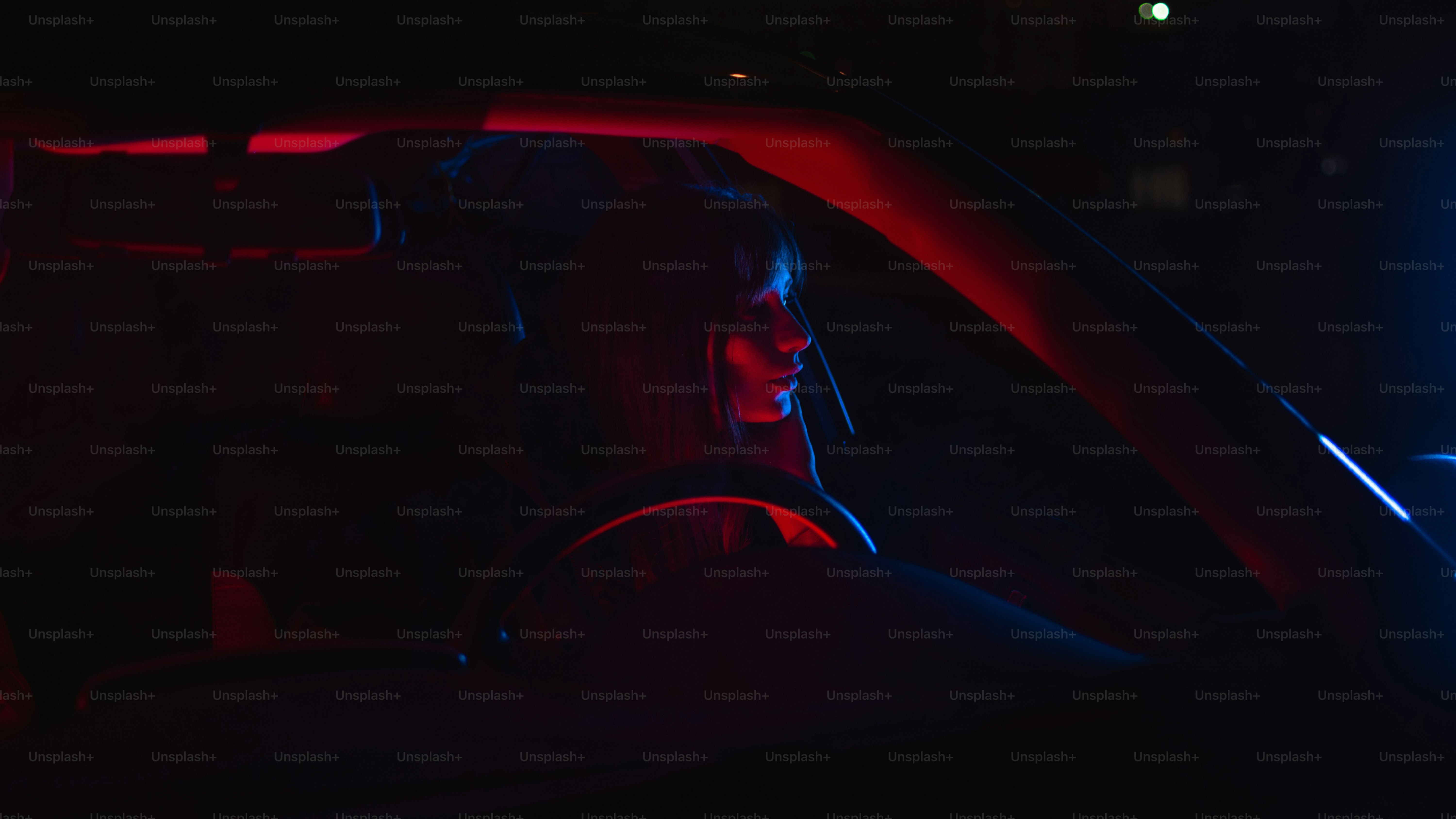 La persona se sienta en el automóvil, iluminada por luces rojas y azules.