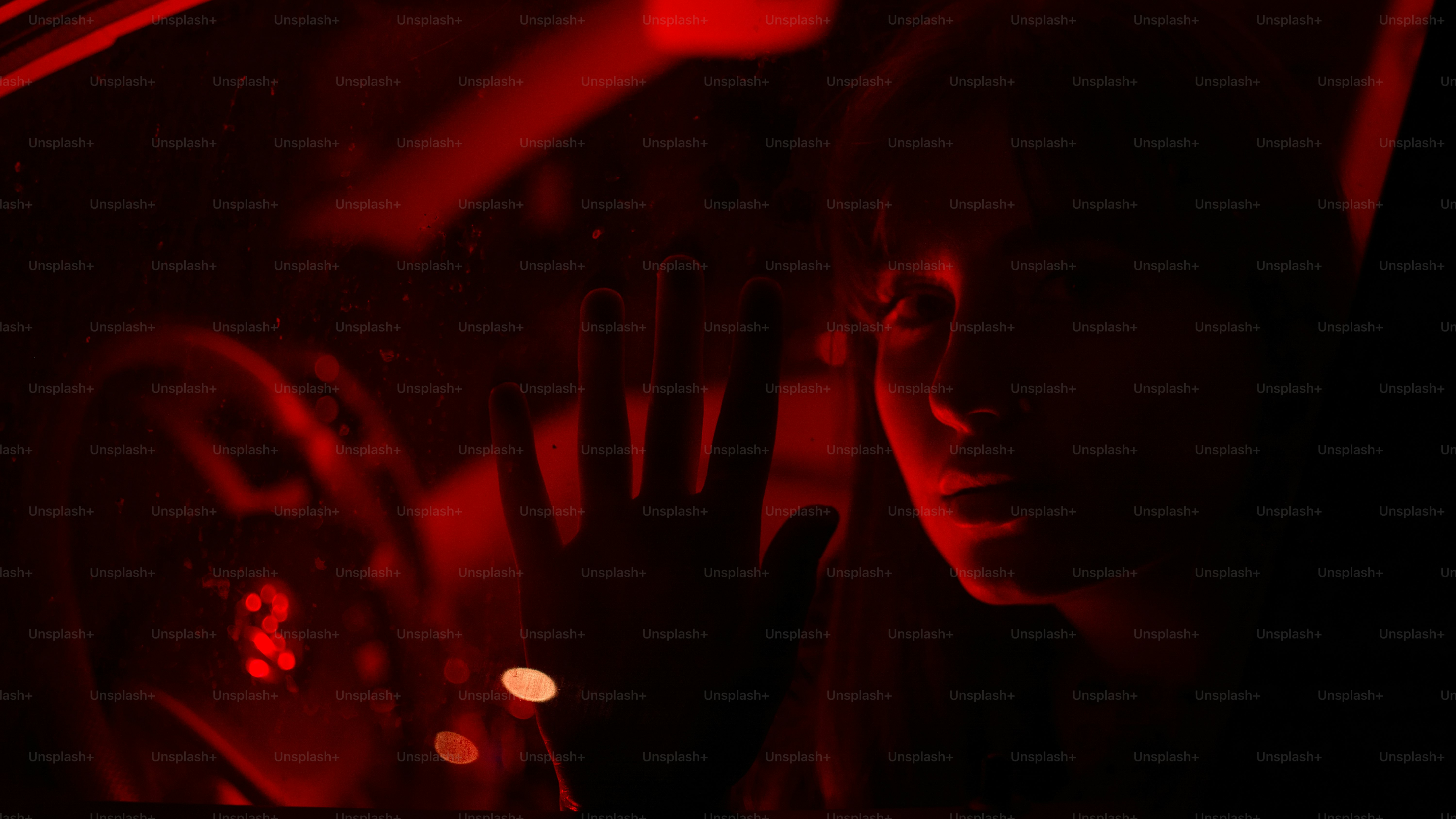 La mano de una persona toca el vidrio con un resplandor rojo.