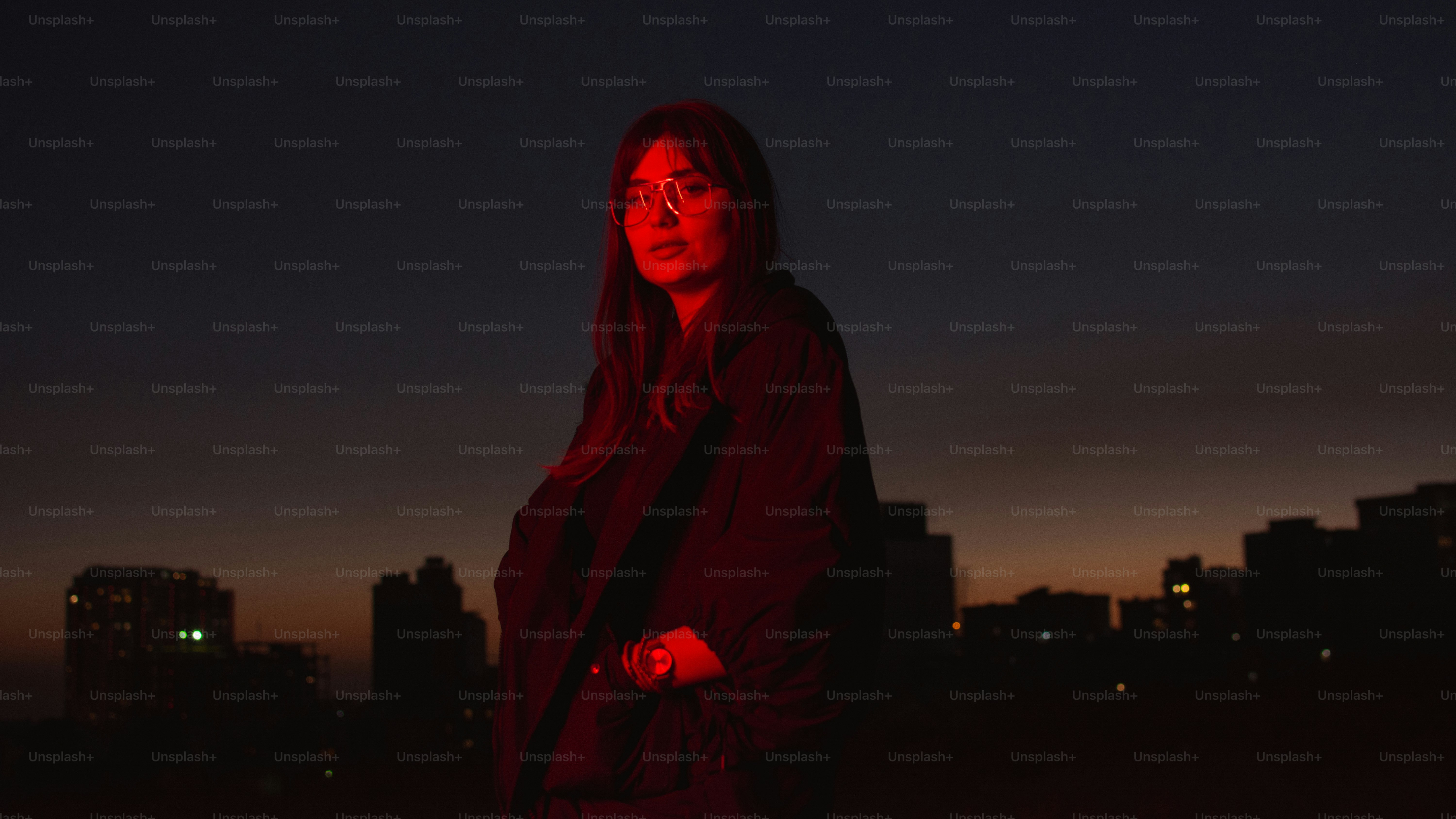 Una persona está iluminada por una luz roja al anochecer.