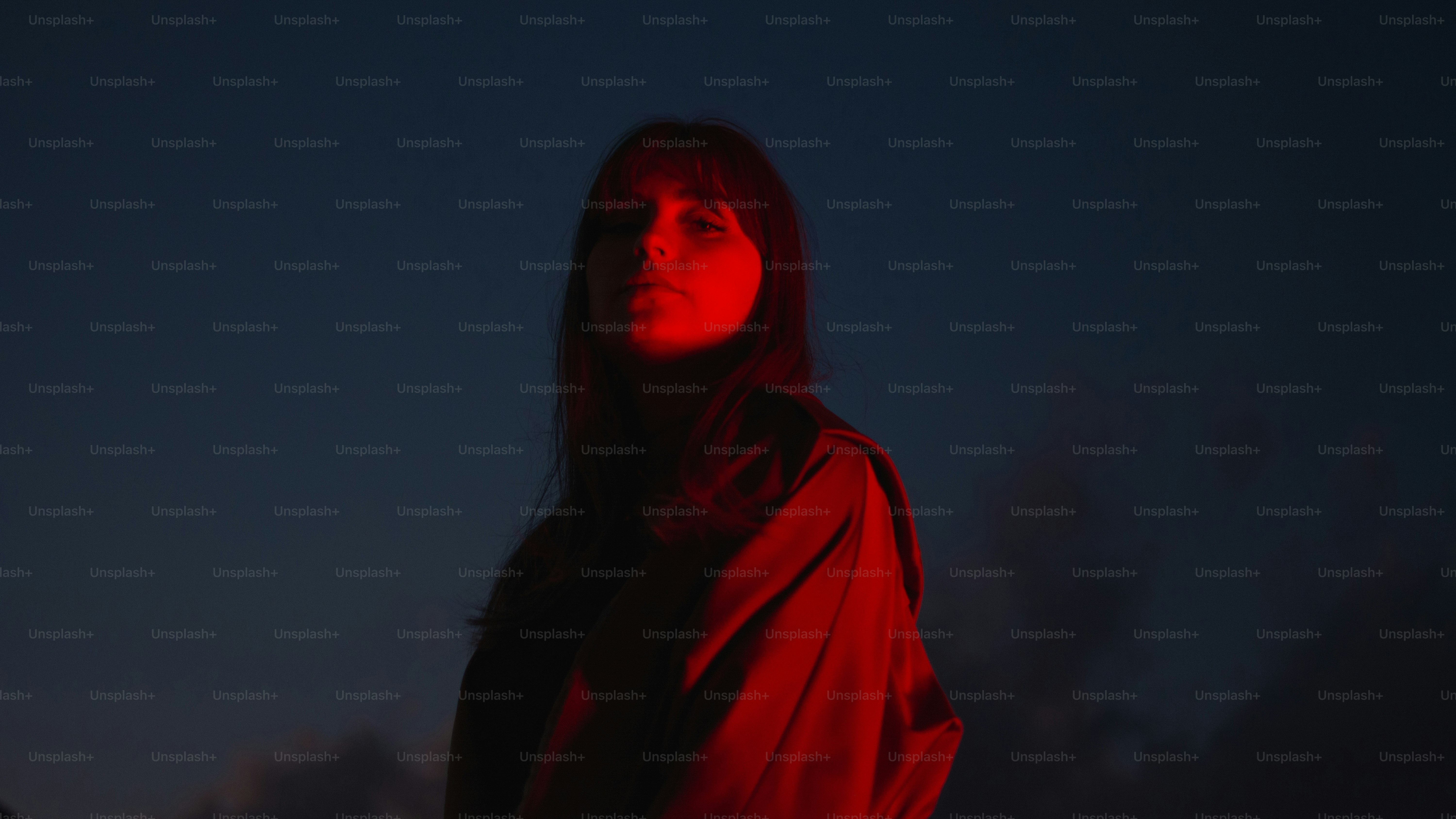 La mujer brilla bajo la luz roja en la oscuridad.