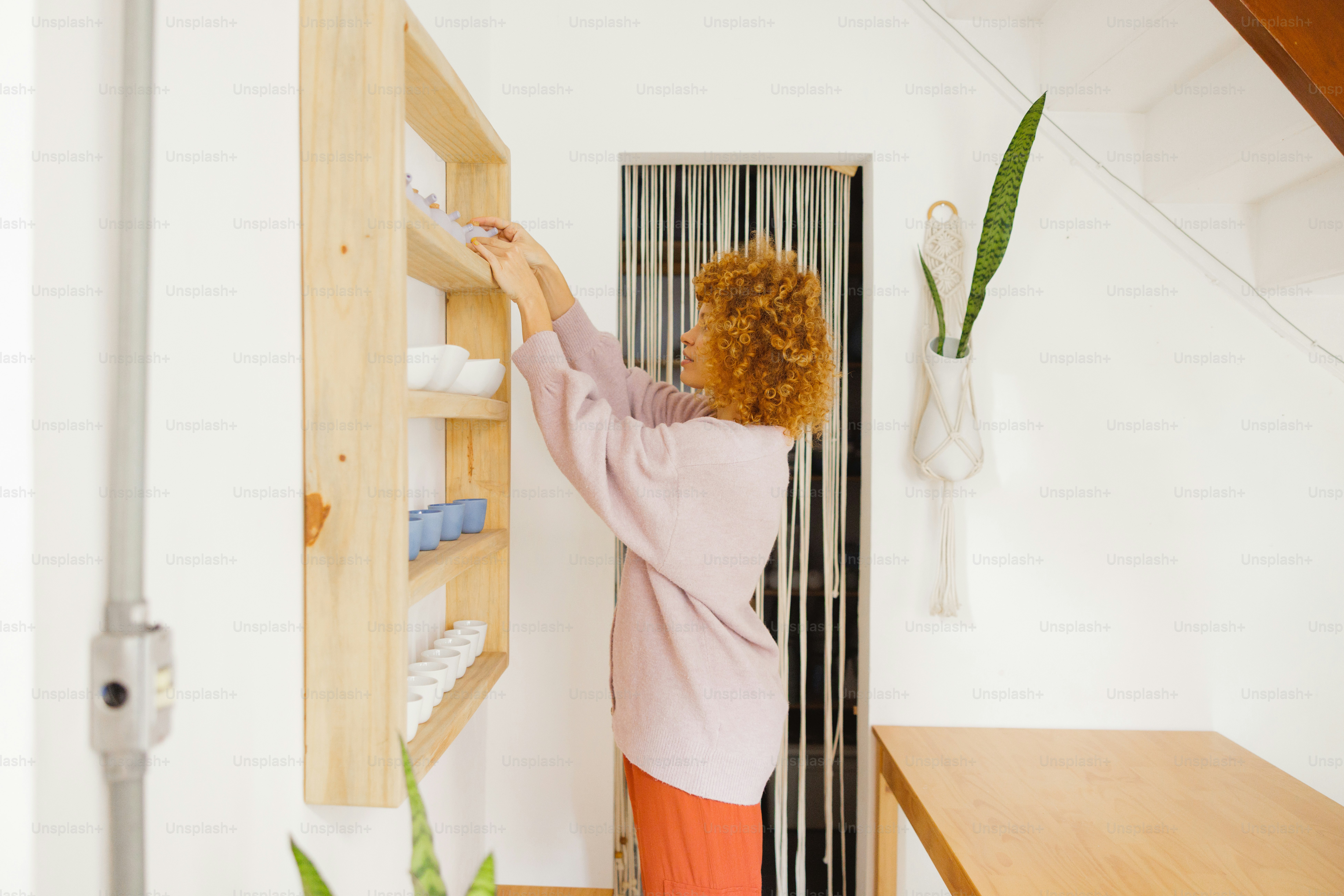 Woman organizing items on wooden shelves.