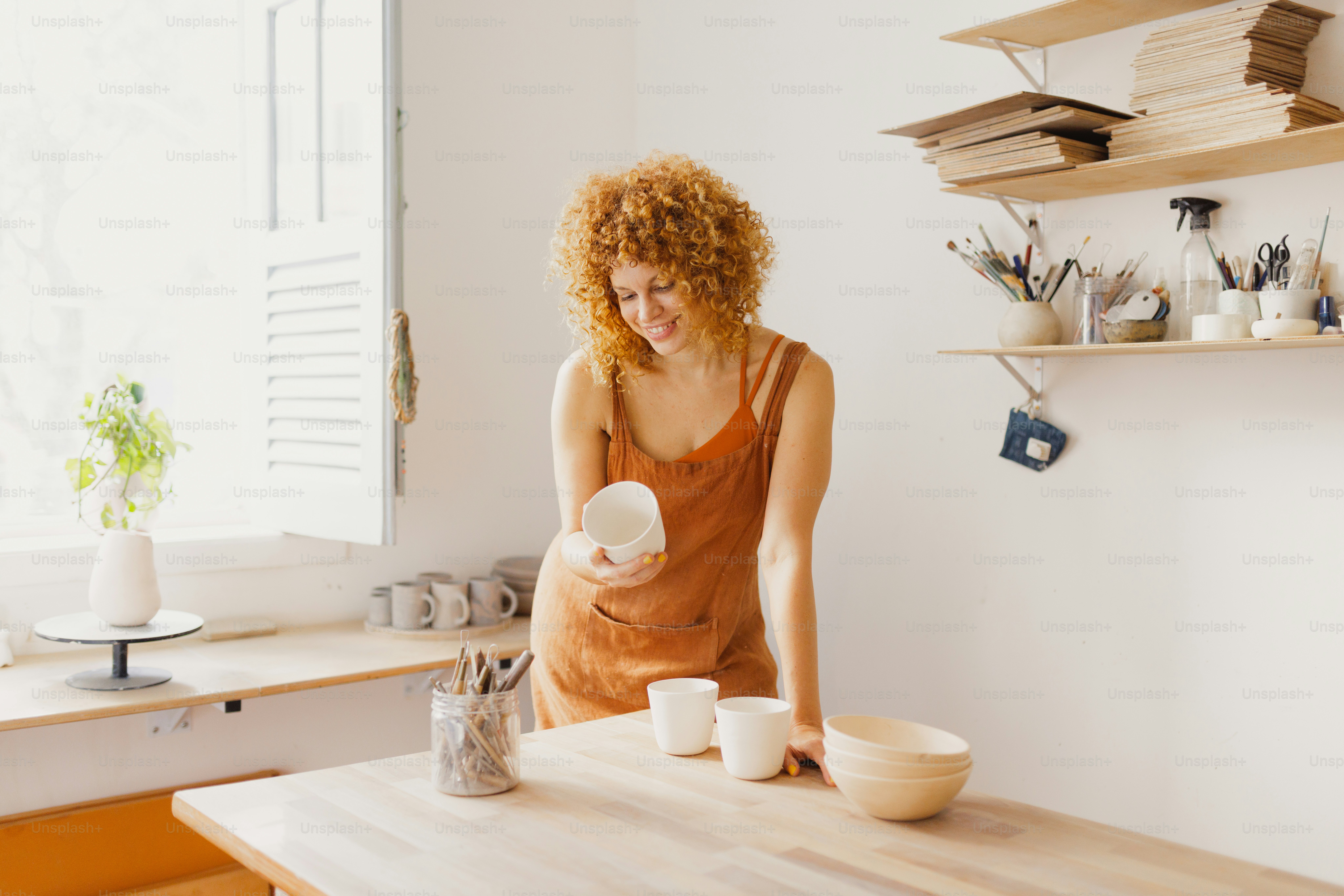 여자가 도자기 공방에서 도자기를 들고 있다.