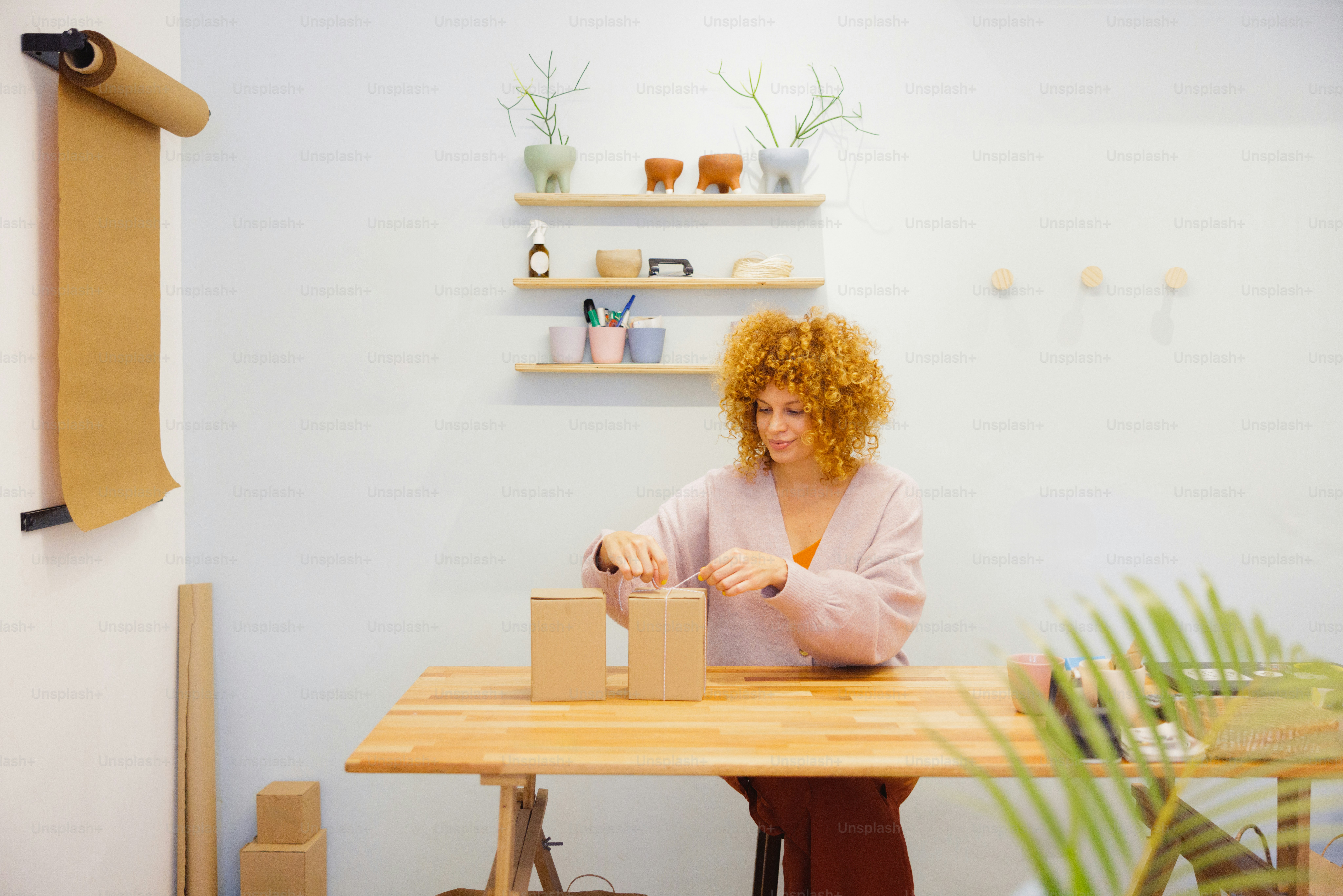A woman packages boxes at a wooden table.