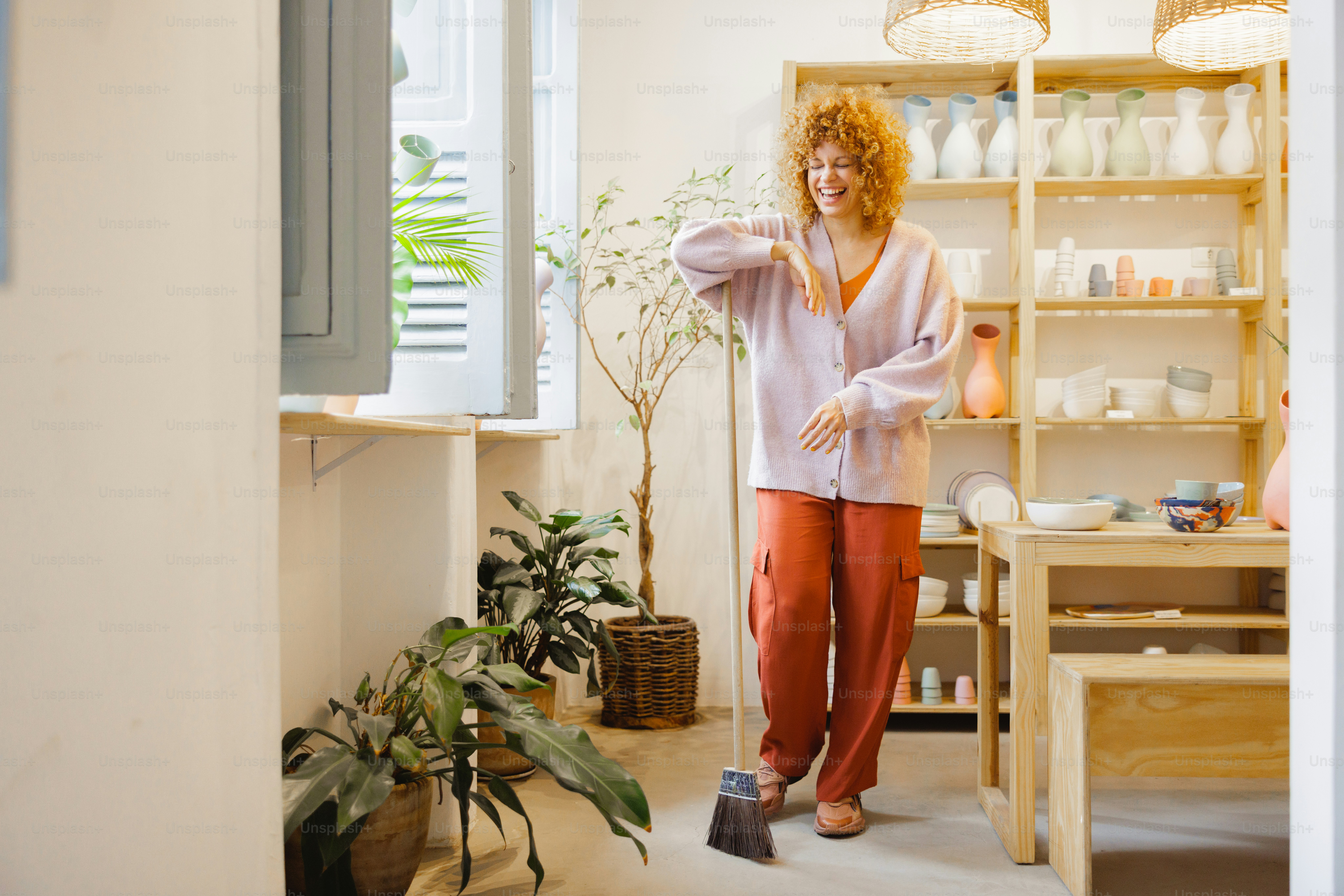 Woman sweeps the floor in a bright and airy kitchen.