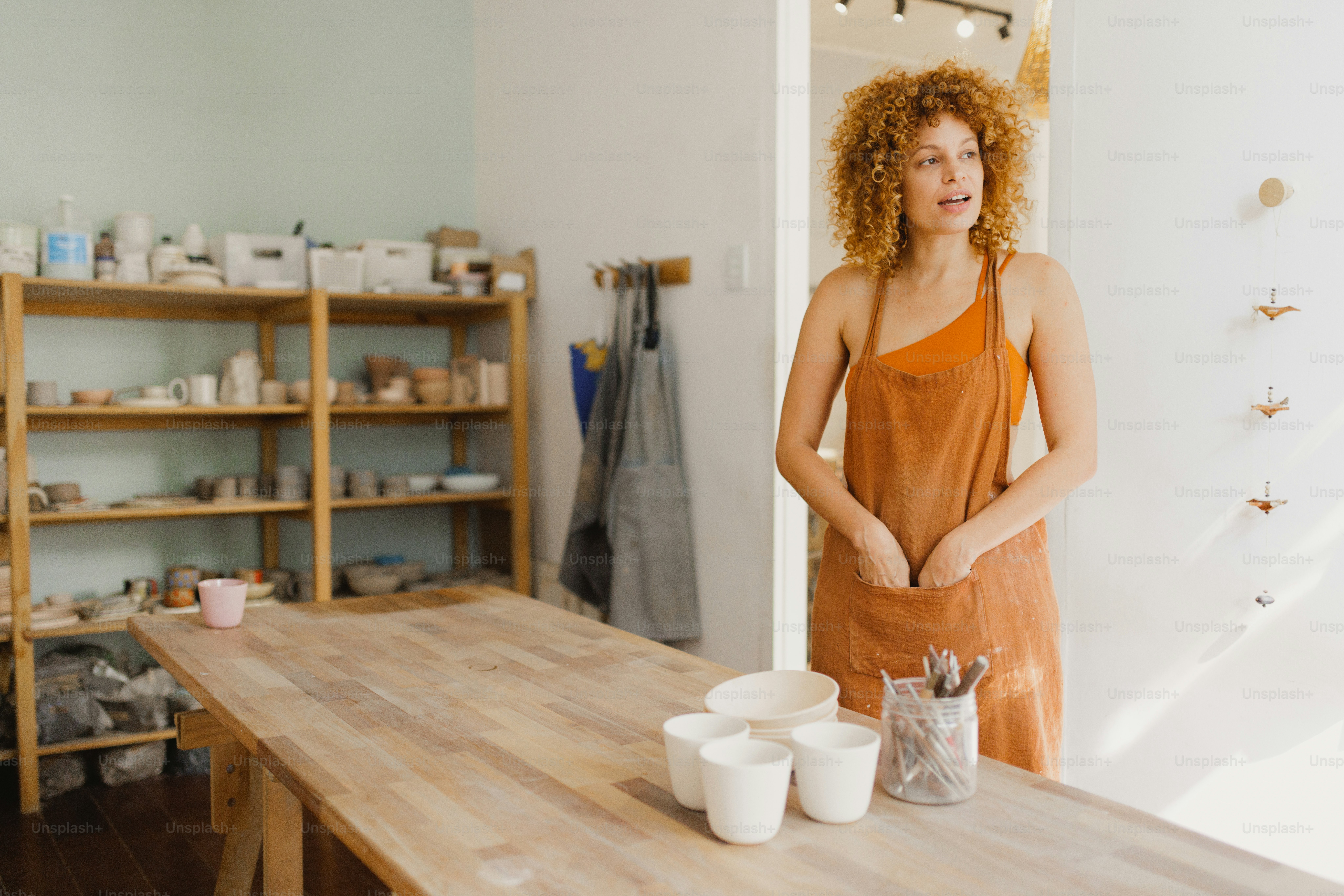 A potter stands in her studio, looking serene.