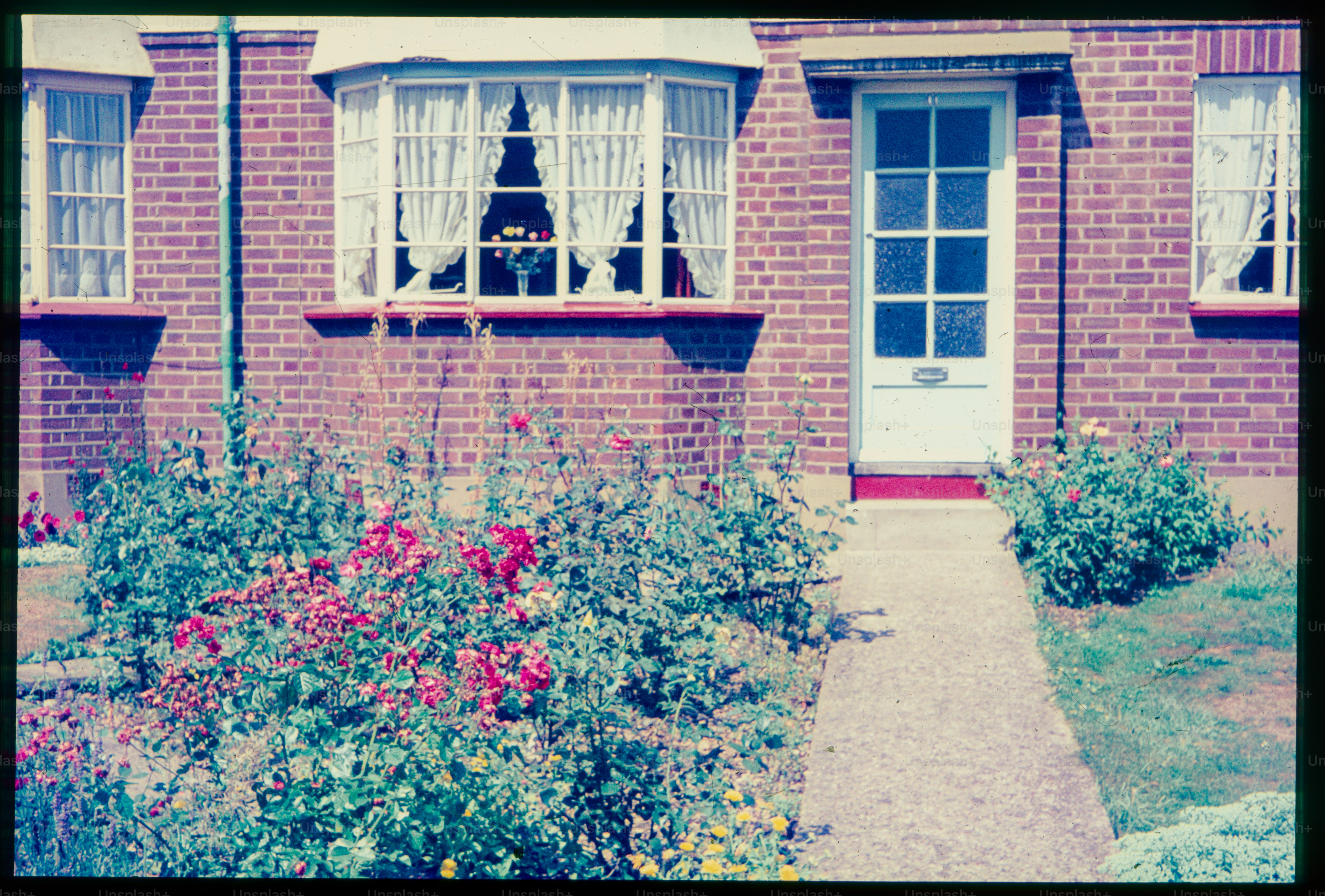 A brick home with flowers welcomes the viewer