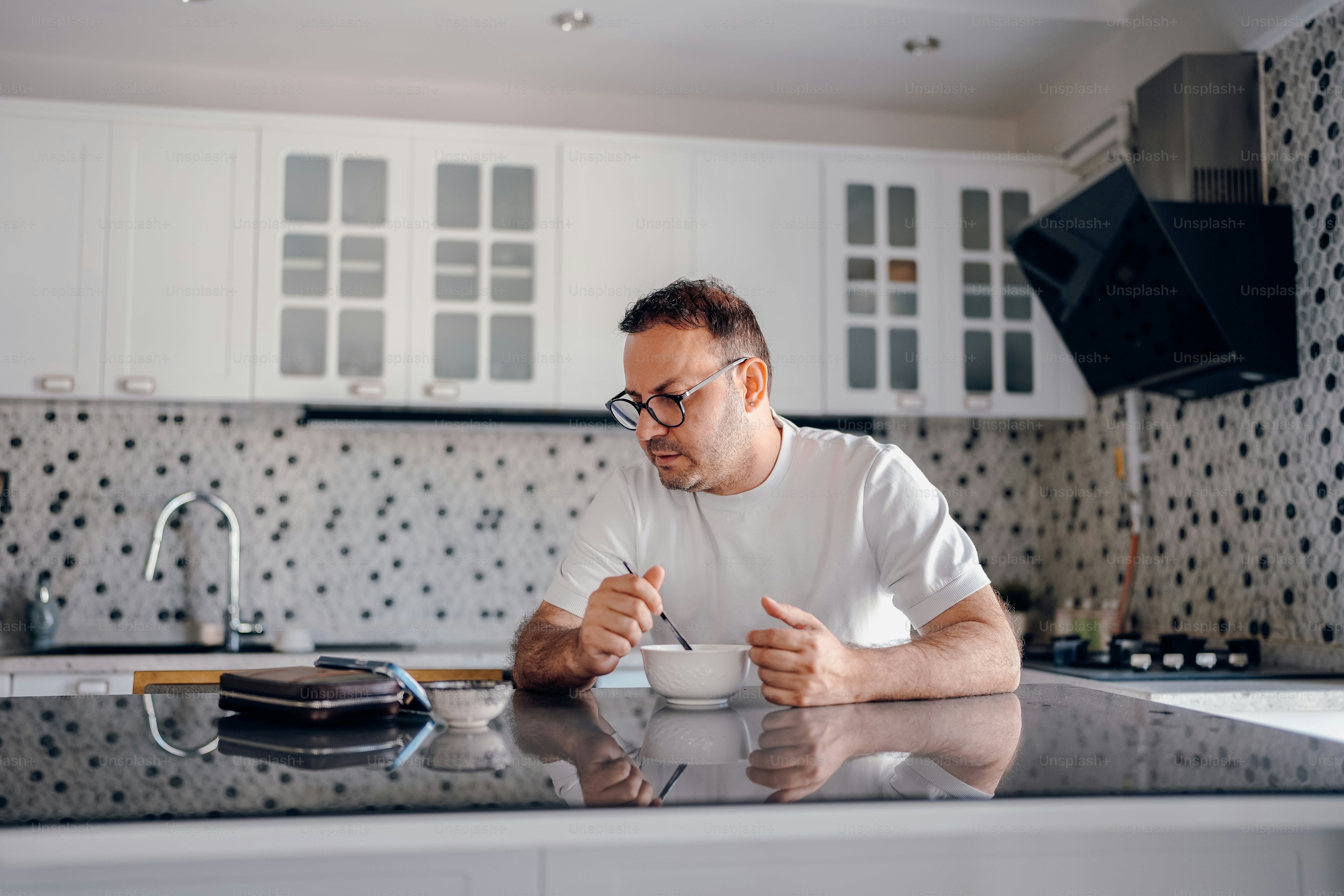 Homem toma café da manhã no balcão da cozinha.