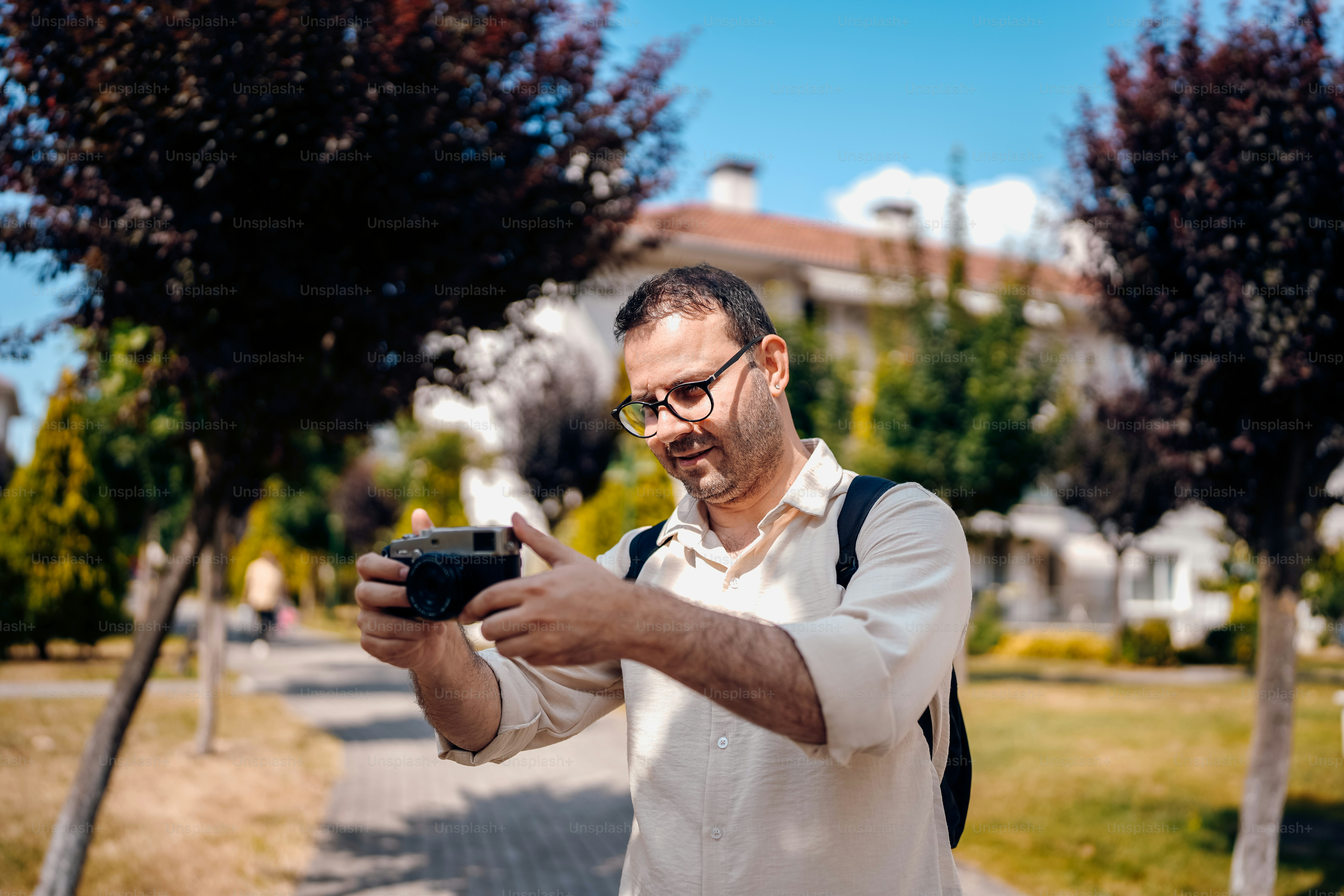 A man smiles while taking a photo outside.