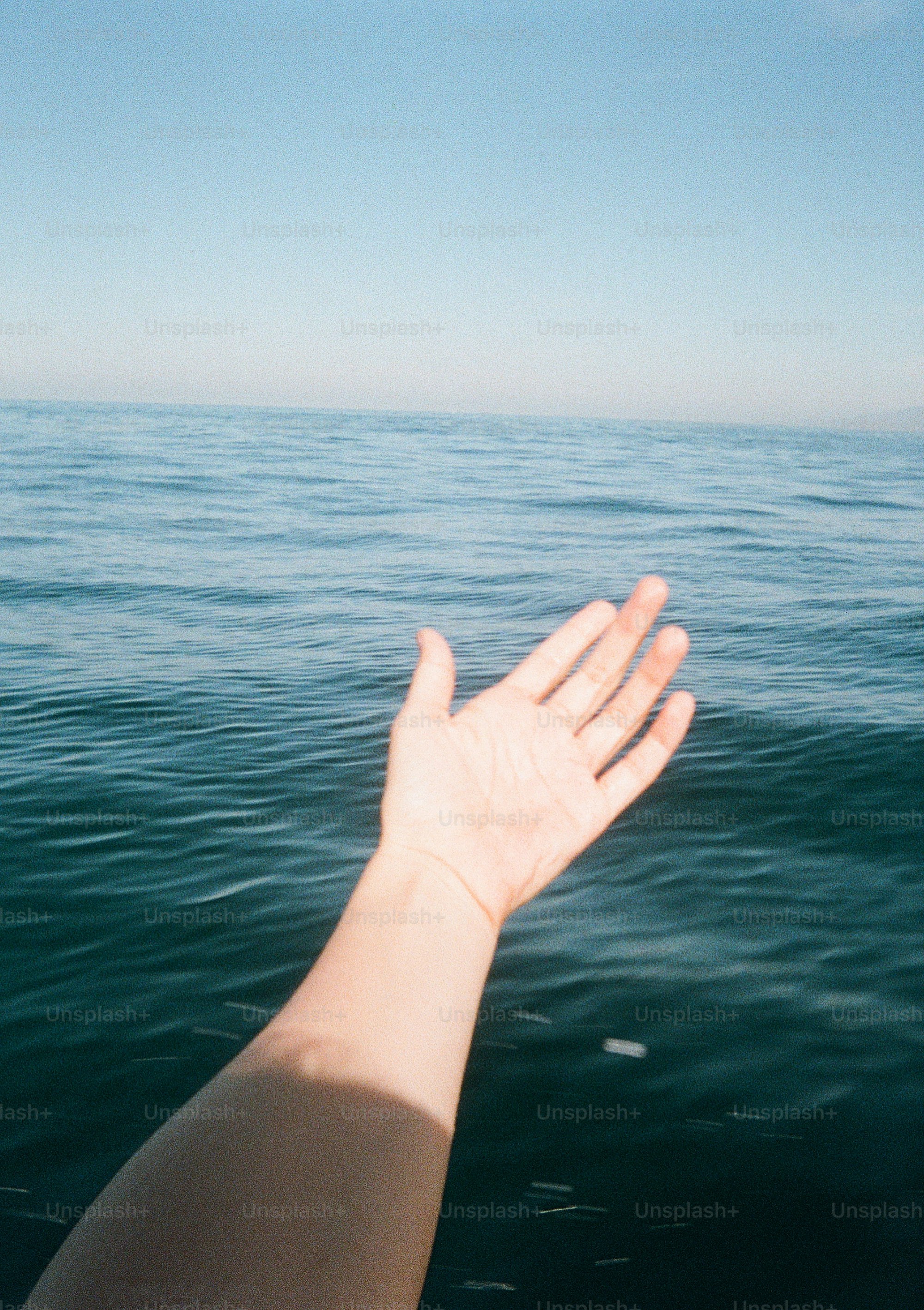 Hand reaches towards the vast, blue ocean. photo – Film photography ...