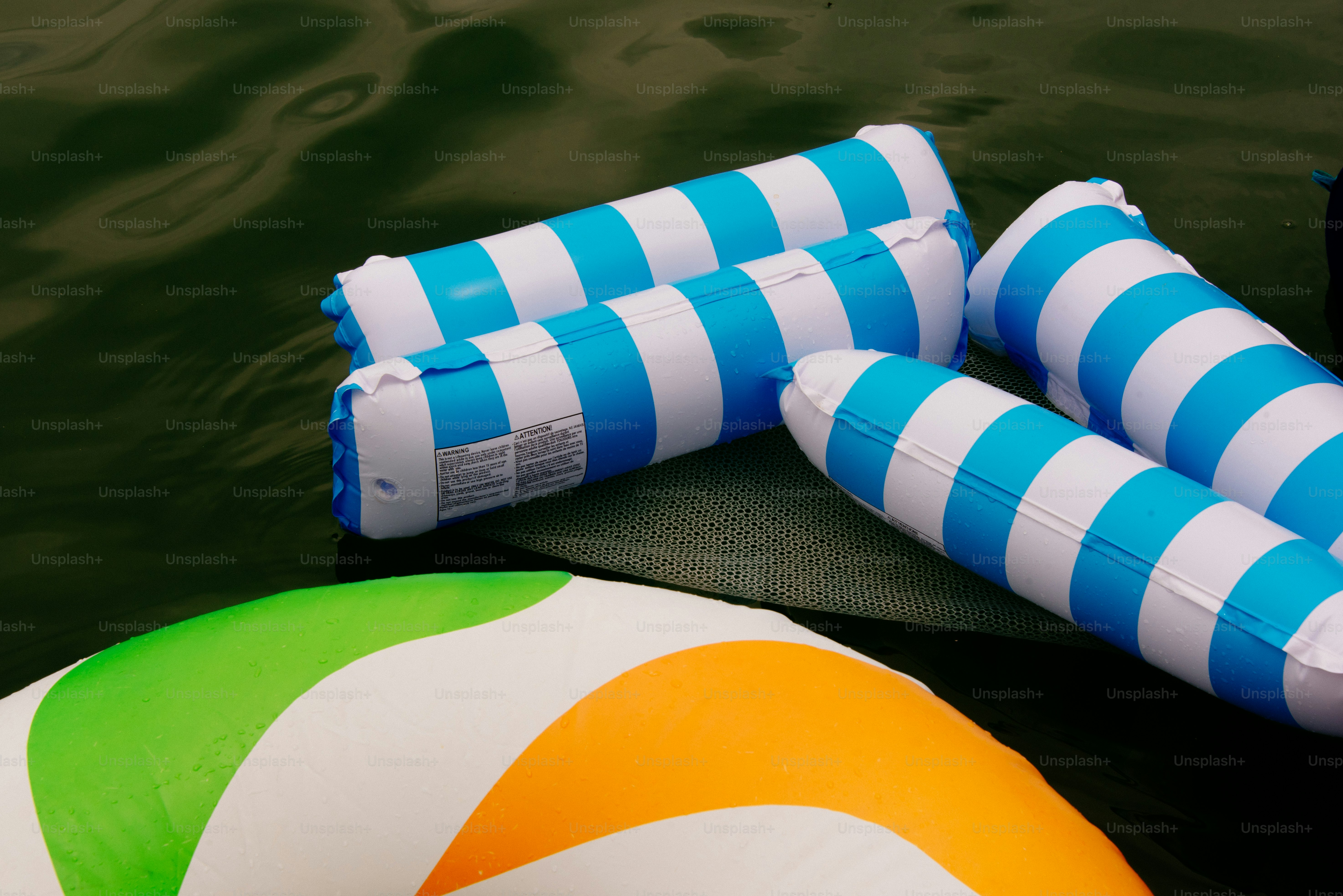 Blue and white striped pool floats rest on the water. photo – Summer ...