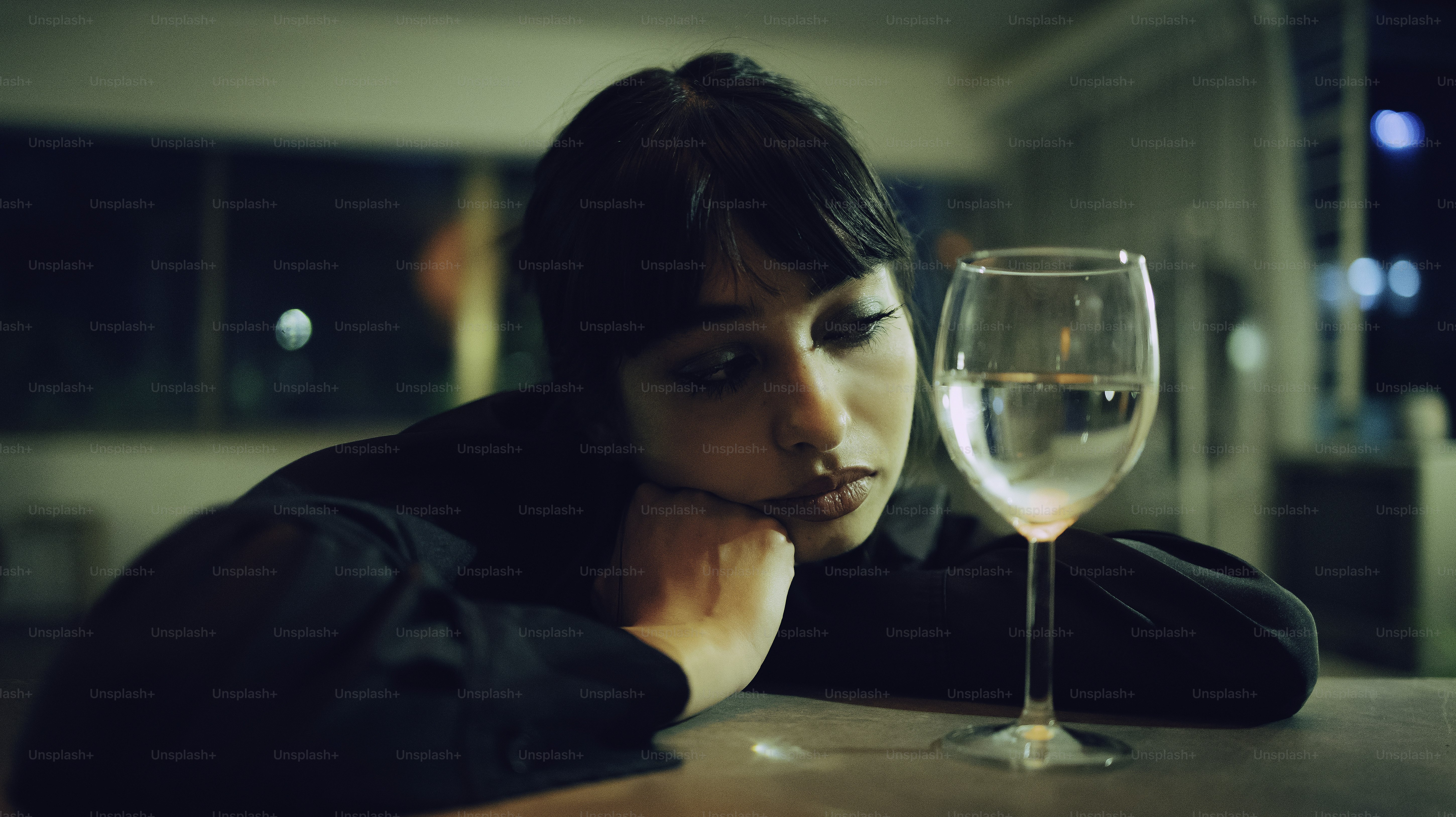 A woman looks sadly at a glass of water