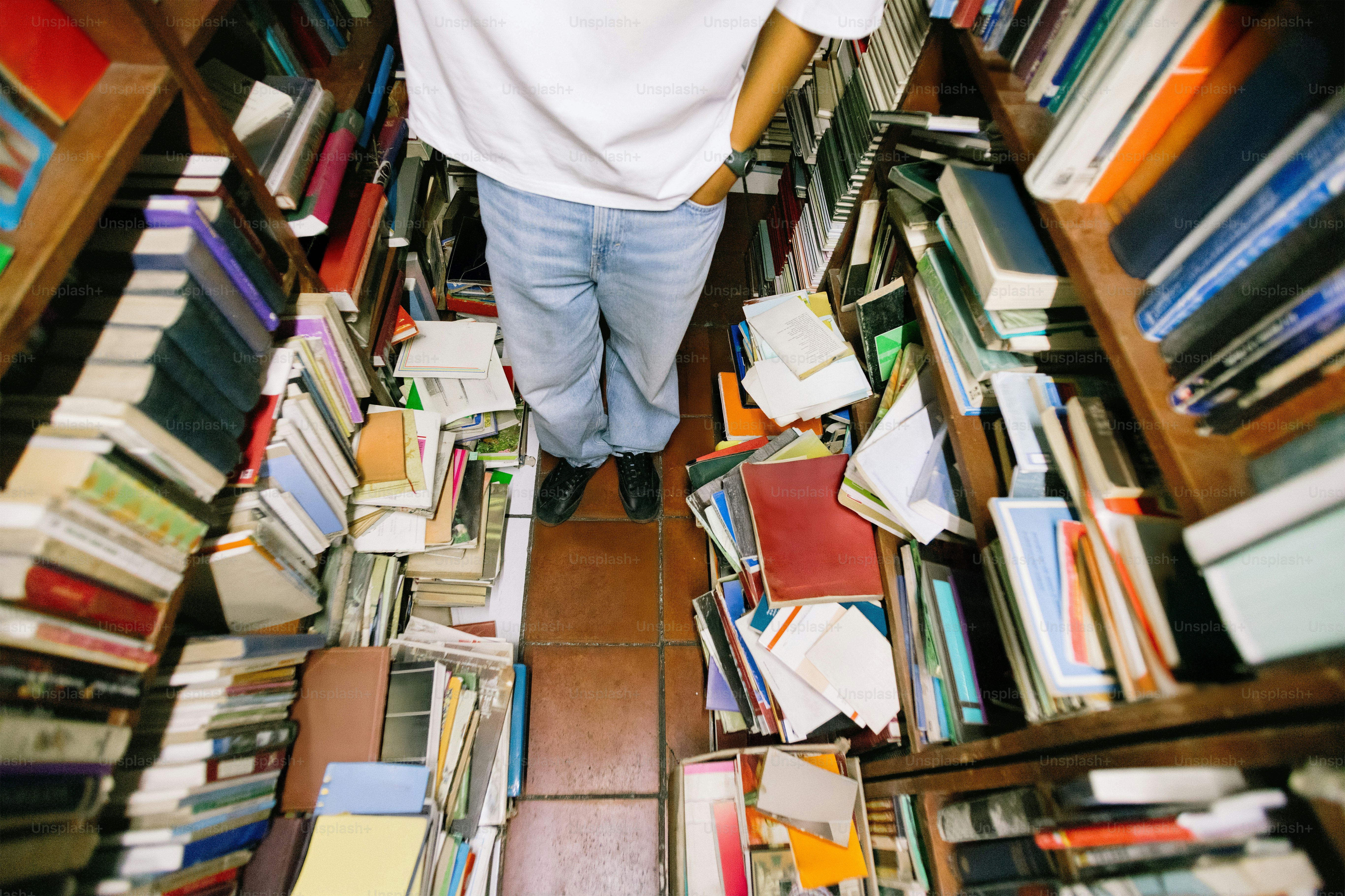 Una persona hojea rodeada de libros en una librería.