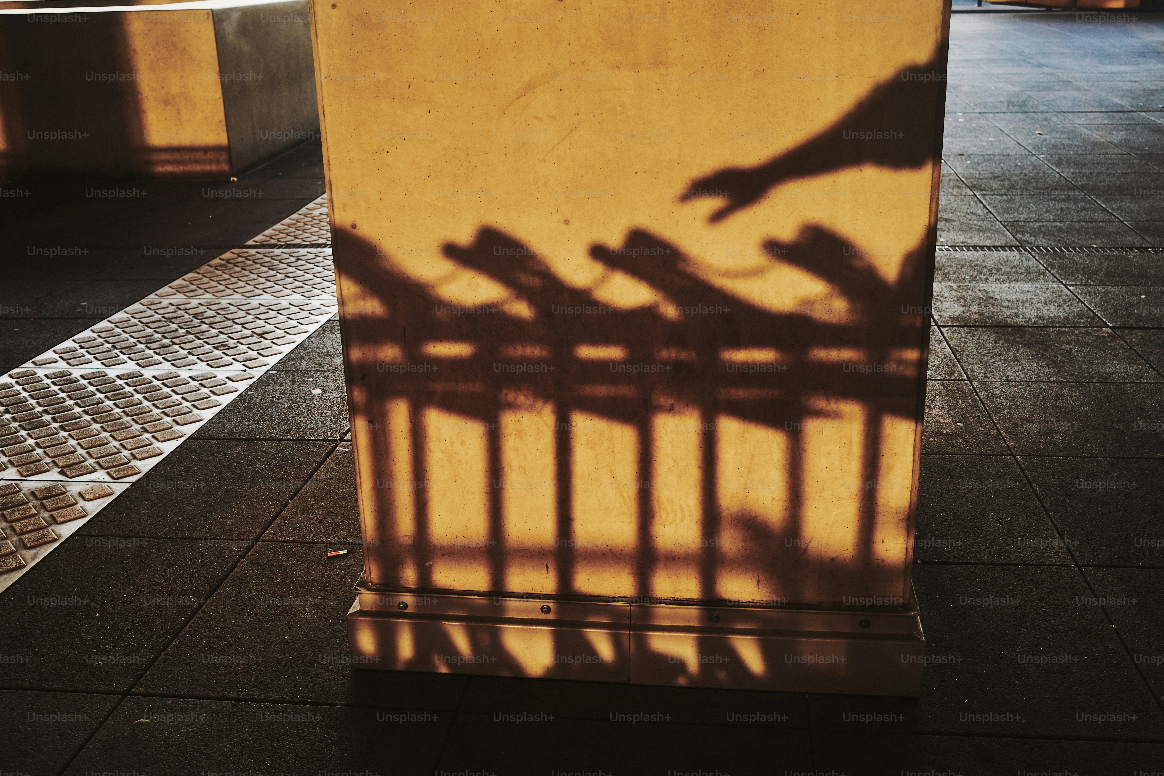 Shadows of a fence and hand are cast on a wall. photo – Abstract Image ...